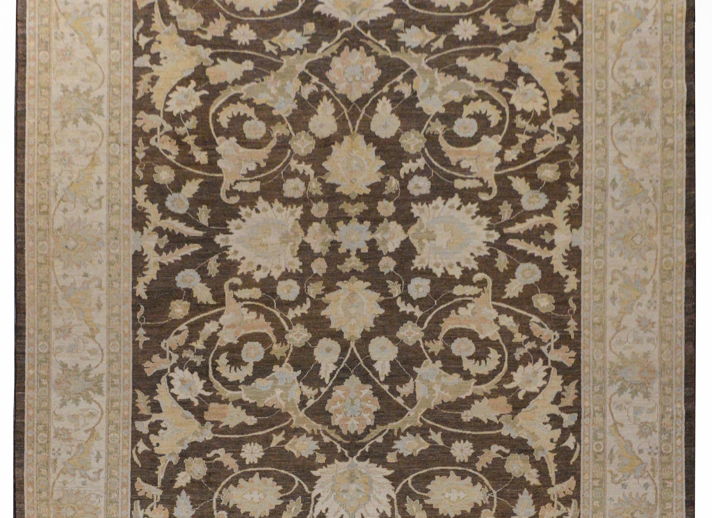 Un merveilleux tapis pakistanais vintage avec un champ de grandes fleurs et de vignes défilantes tissées dans des tons bleus, verts et dorés, sur un fond brun foncé. La bordure est exceptionnelle avec une bordure aux motifs et aux couleurs