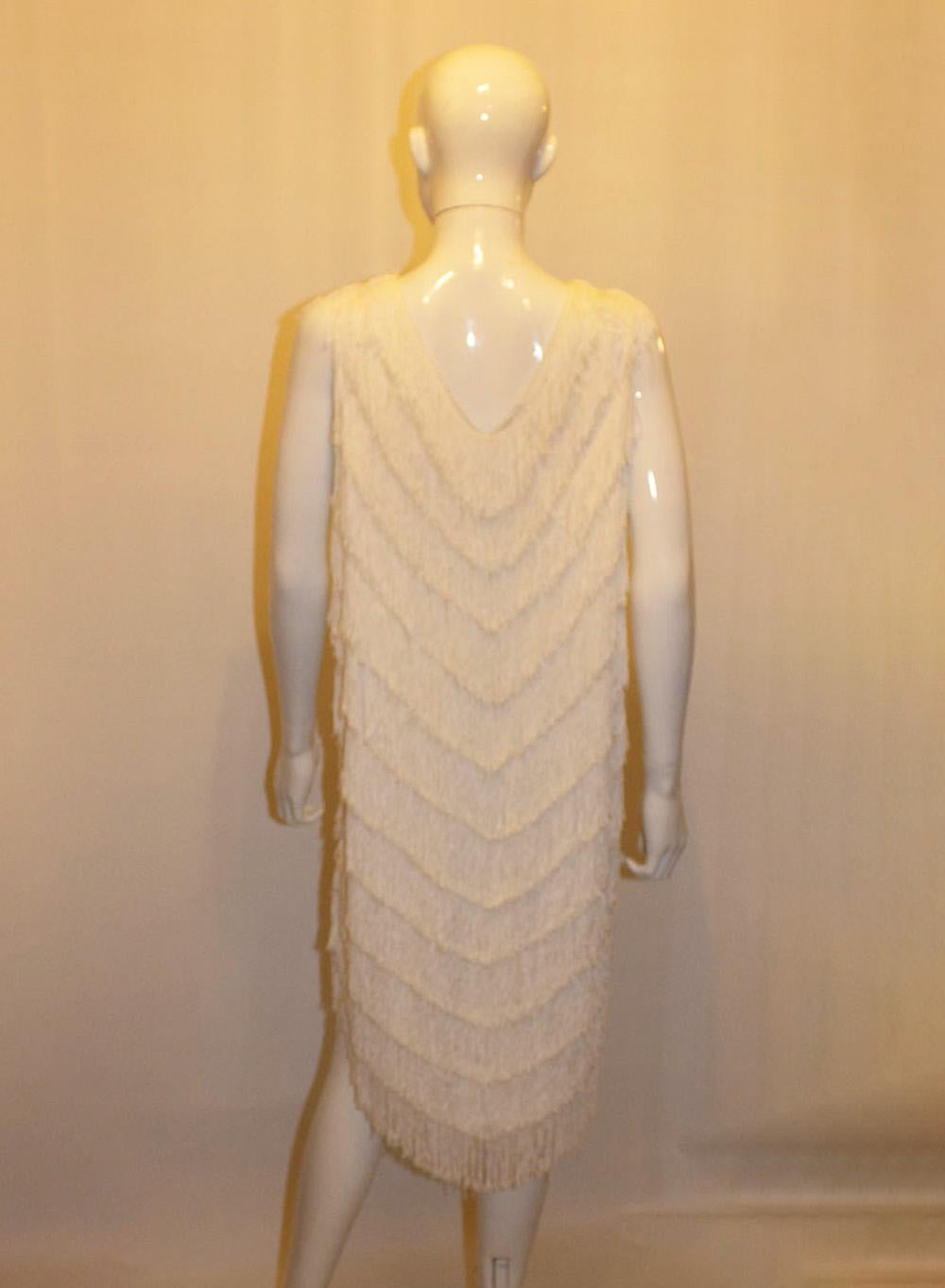 A fun and flirty  vintage white fringed evening dress, perfect for a party or wedding. The dress has a v neckline, is sleaveless  and has several rows of fringing that move when you do.  It is fully lined. 
Measurements: Bust up to 43'', length 38''