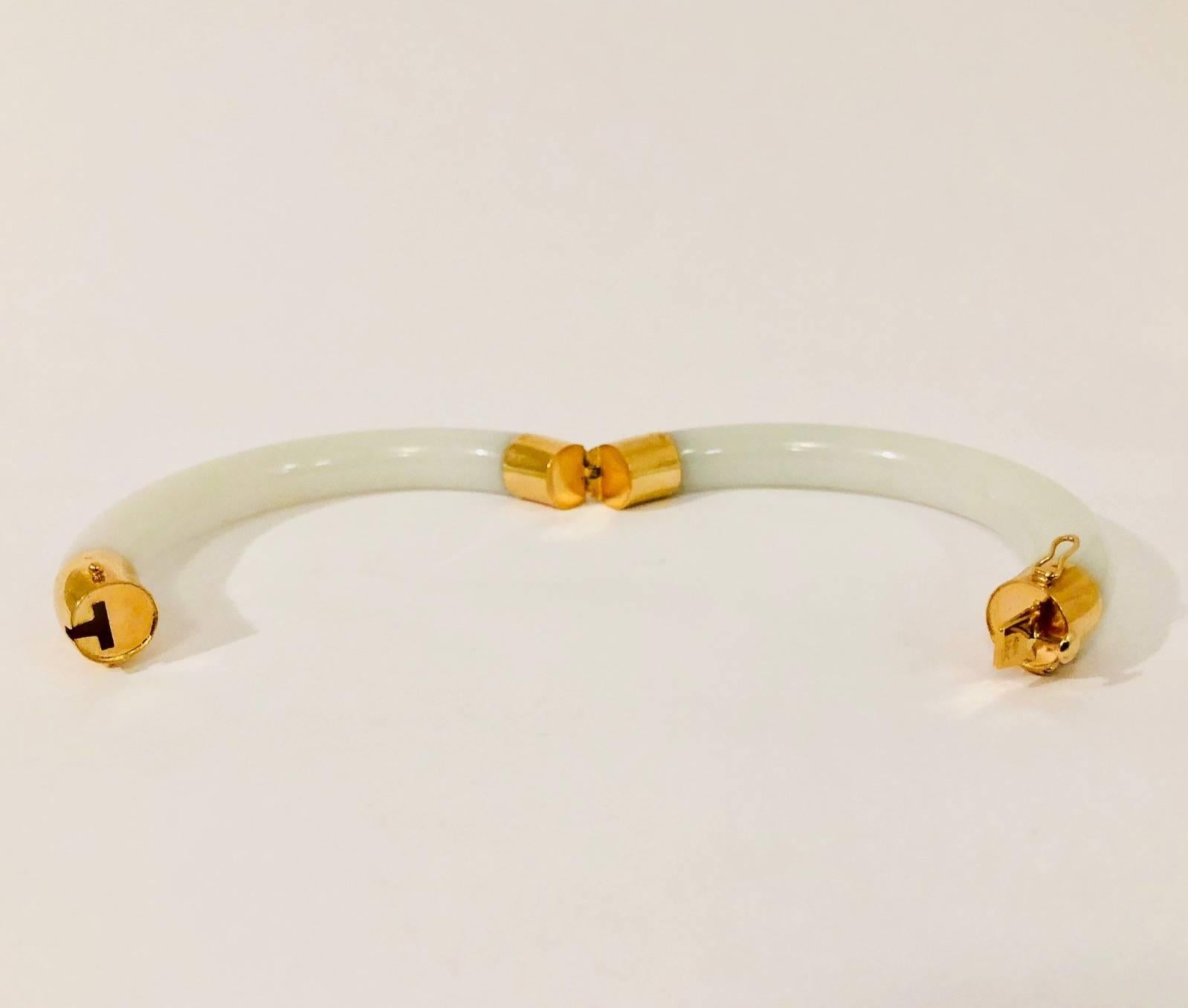 An absolutely classic white jade bangle with 14 karat yellow gold end caps.  One end cap opens for total ease of use.  Secured on each side with a figure 8 safety clasp.  The jade is perfectly smooth and luxurious to touch. Sophisticated addition to