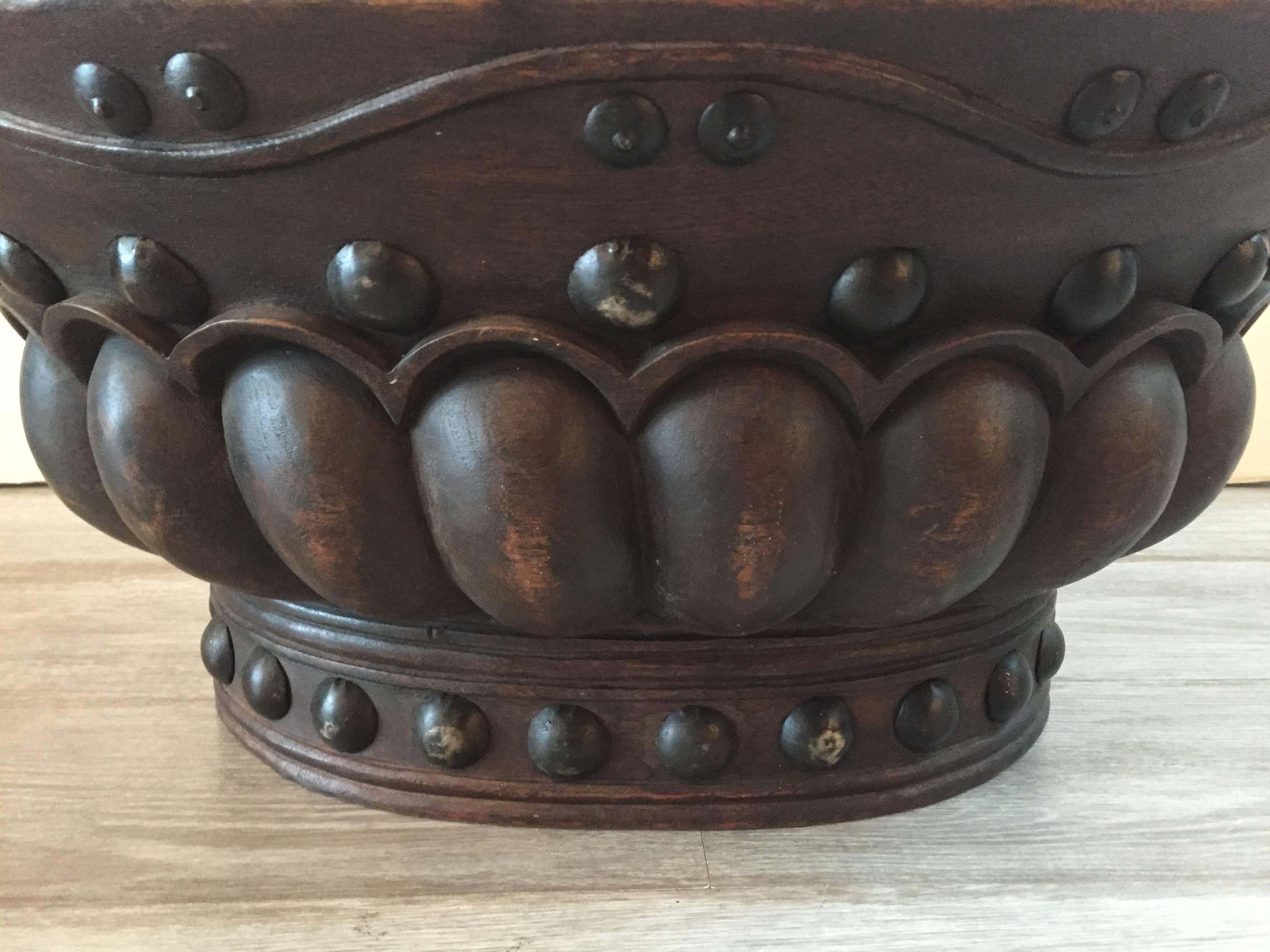 Striking carved oval wood bowl having iron handles and decorative studs.