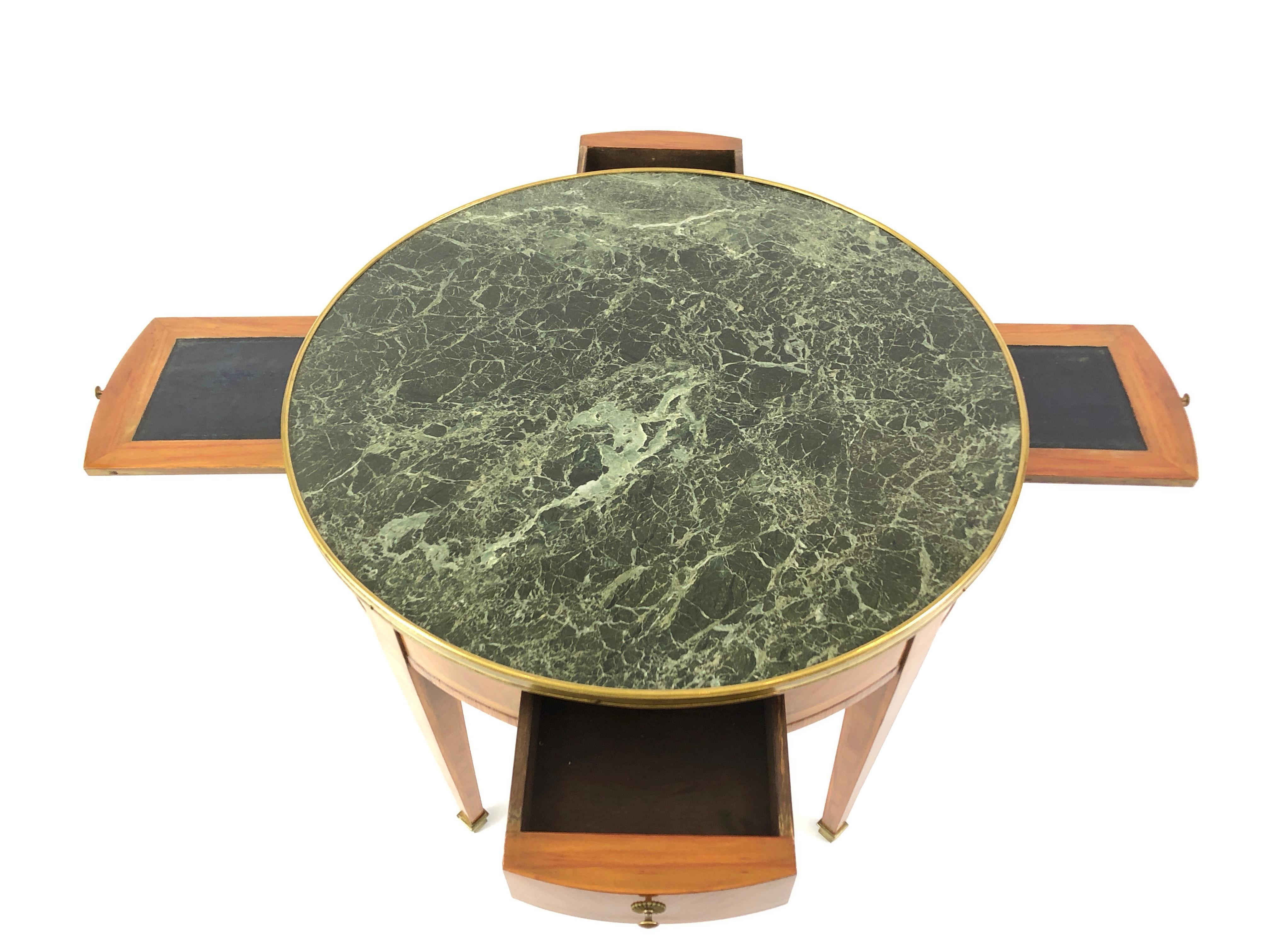 Vintage round French table having a wonderful dark green and cream marble top, brass gallery and gorgeous inlaid satinwood base. The top has 2 drawers and 2 pull out leather trays or slides around the underside periphery-- the slides are a great
