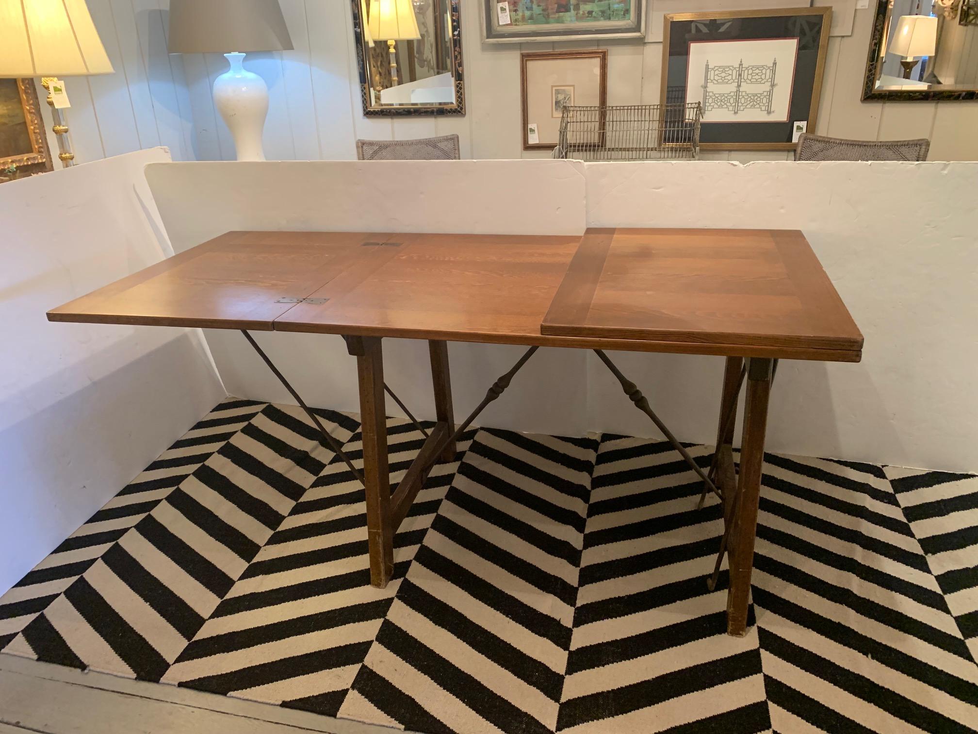 Great looking super versatile Spanish style vintage Douglas fir dining table or work table having folding legs with handsome iron cross bars and a top where each end can fold in to create a smaller table that measures 48 W x 31.75 H x 33.5 D
The