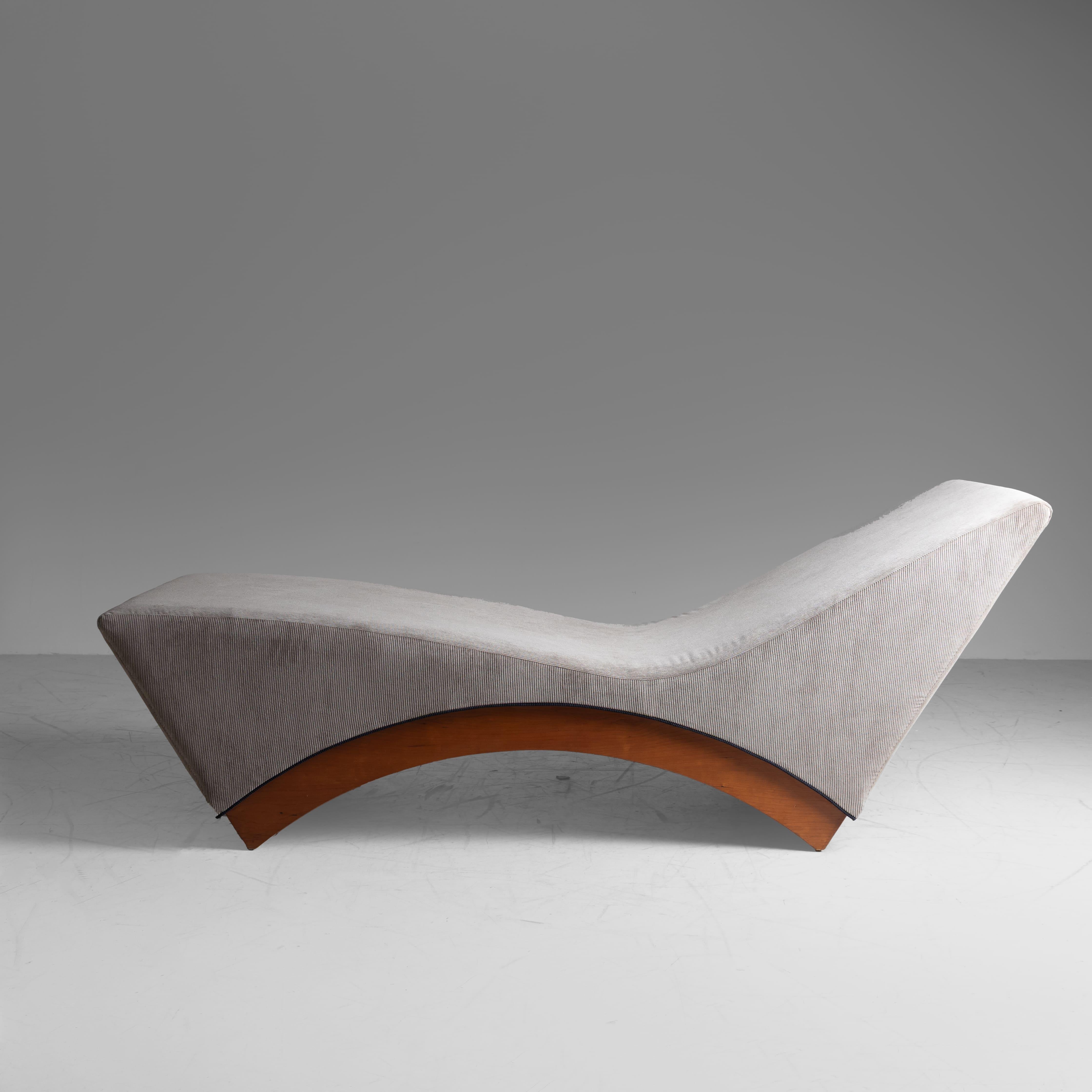 This iconic piece exudes the vibrant spirit of the era channeling both comfort and style. The wooden frame adds a touch of warmth and sophistication, while the fabric upholstery enhances its plush, inviting appeal. The chaise longue's sleek lines