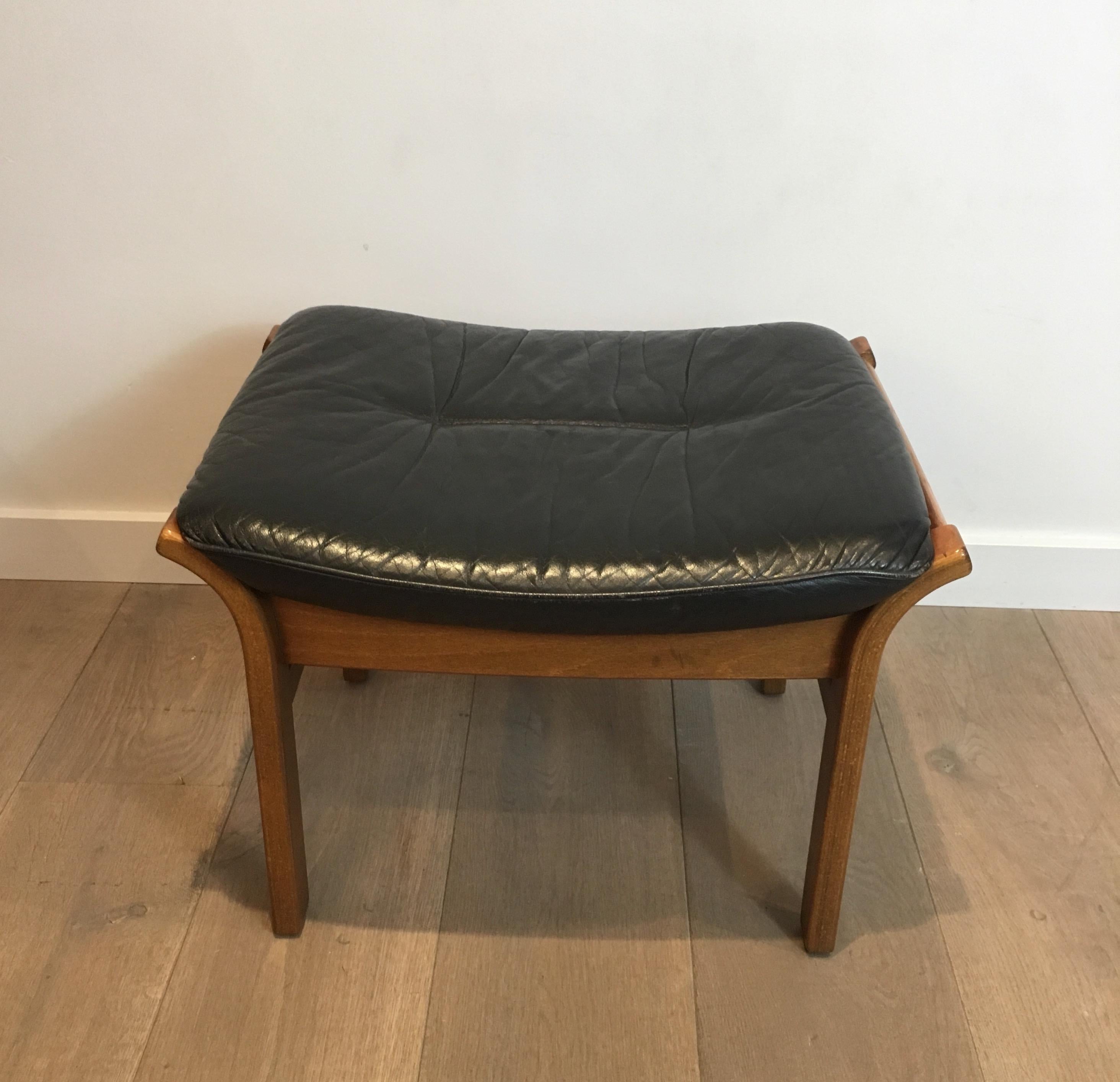 This design stool is made of wood with a black leather seat. This is a French work, circa 1970.