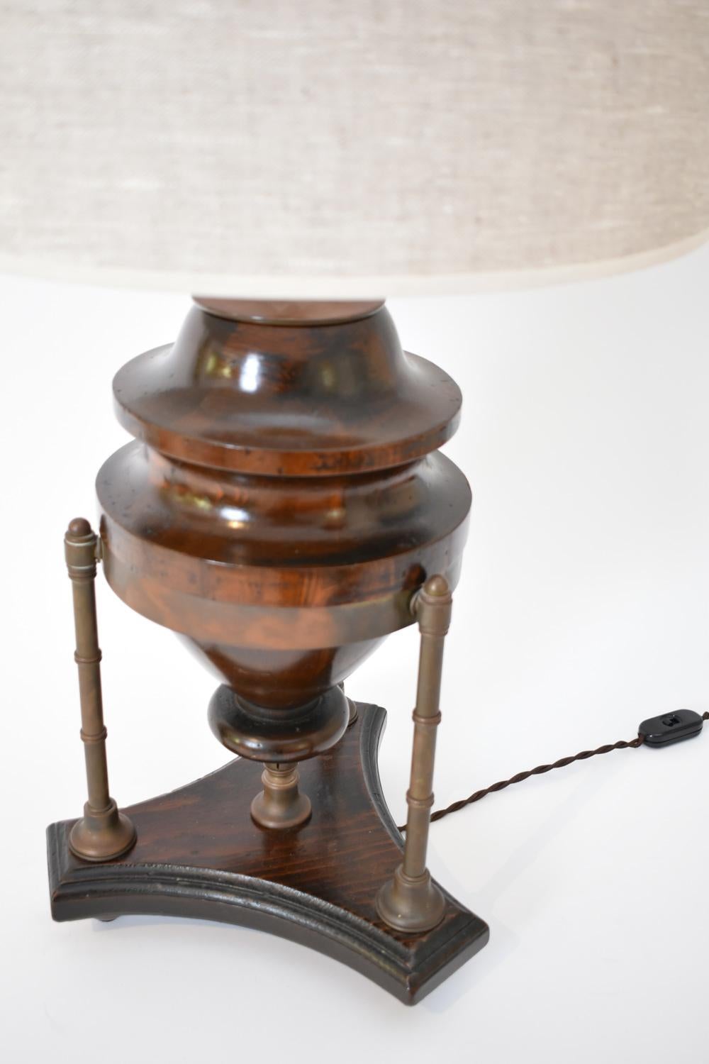 Lampada a forma di balaustro in legno naturale che poggia su una base a treppiede con montanti in ottone che imitano il bambù. USA, anni '10.
