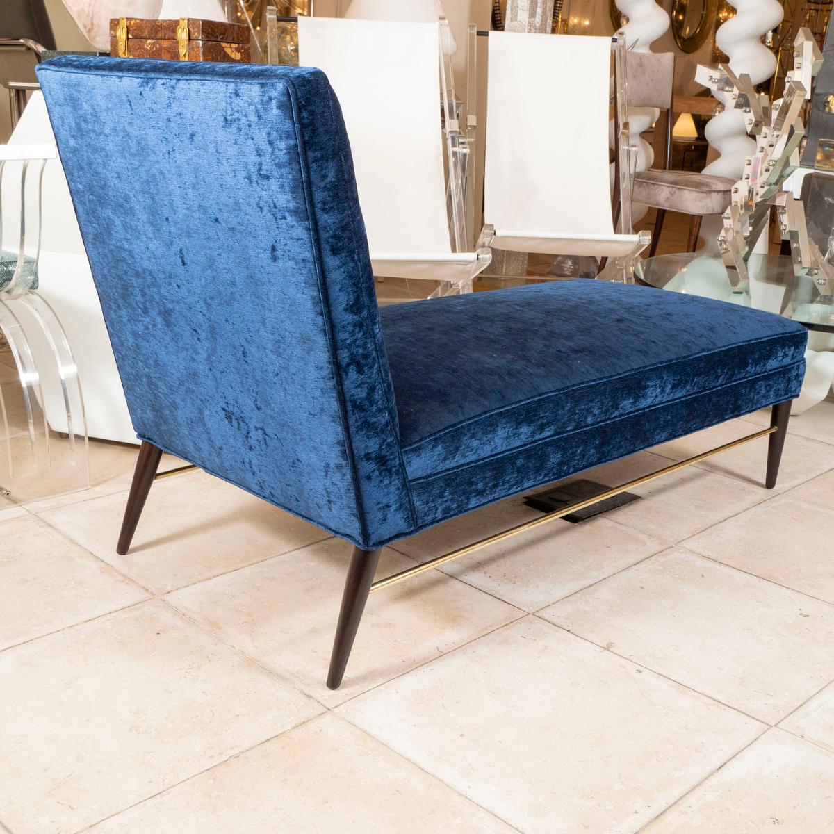 Wood and brass upholstered chaise lounge by Paul McCobb. Upholstered in a dark blue velvet fabric.