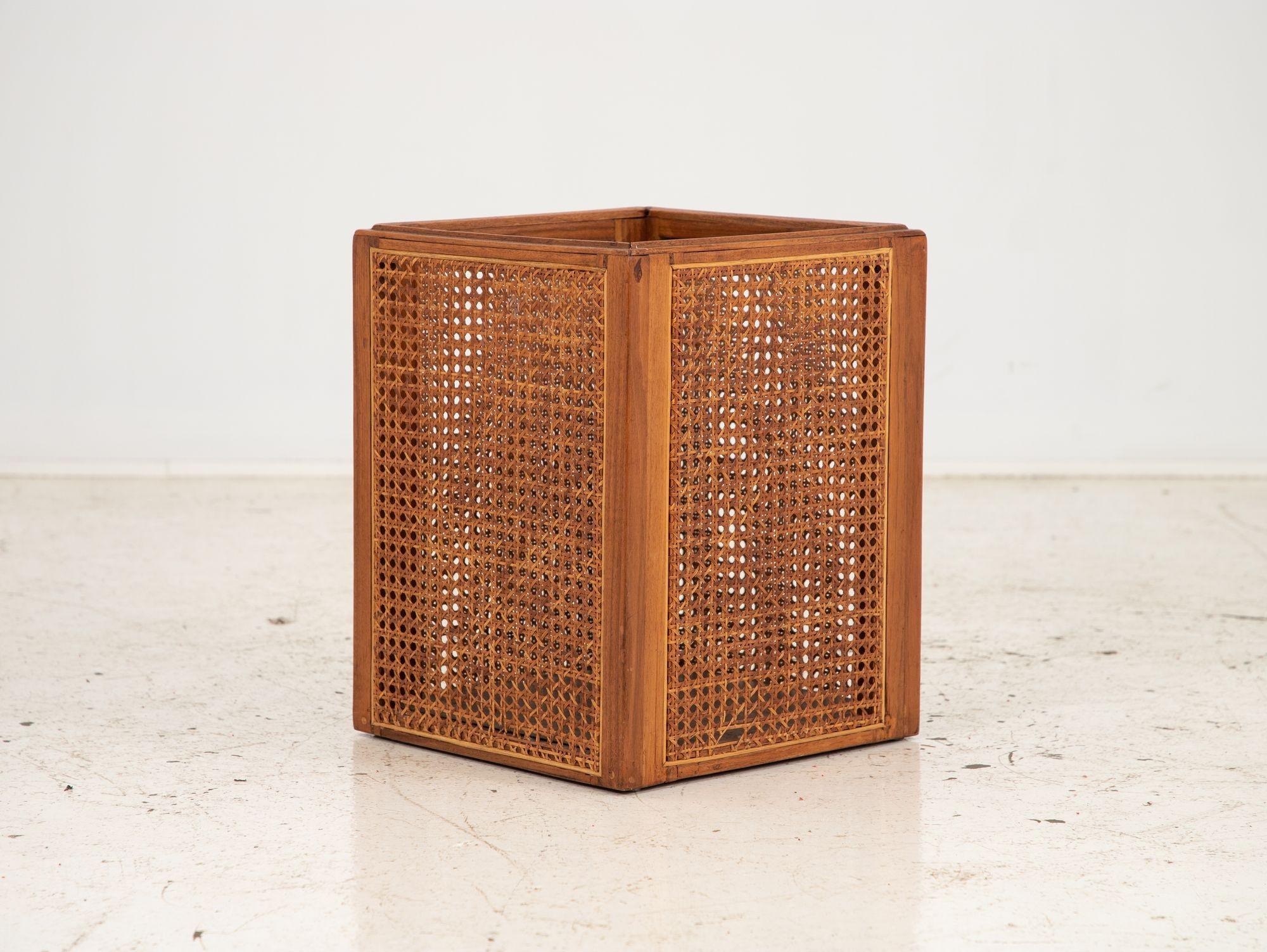 Questo elegante cestino quadrato è dotato di una robusta struttura in legno che aggiunge un tocco di raffinatezza a qualsiasi ambiente. Ognuno dei quattro lati è ornato da pannelli di canna incastonati, che offrono un design elegante e arioso. Il