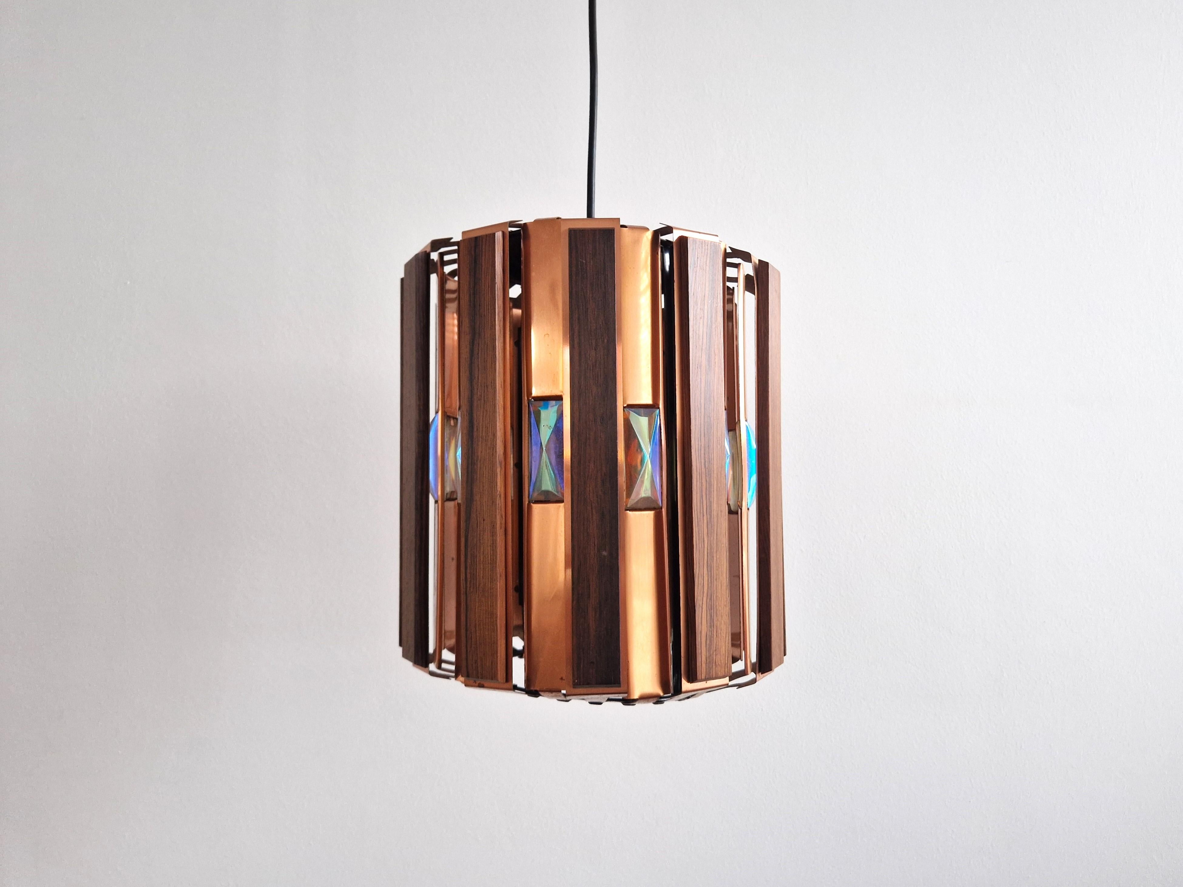 This stunning pendant light was designed by Werner Schou for Coronell Elektro in Denmark in the 1960's. The lamp gives a sculptural light effect, which is very characteristic for the lamps by Werner Schou. It is made out of wooden slats and copper