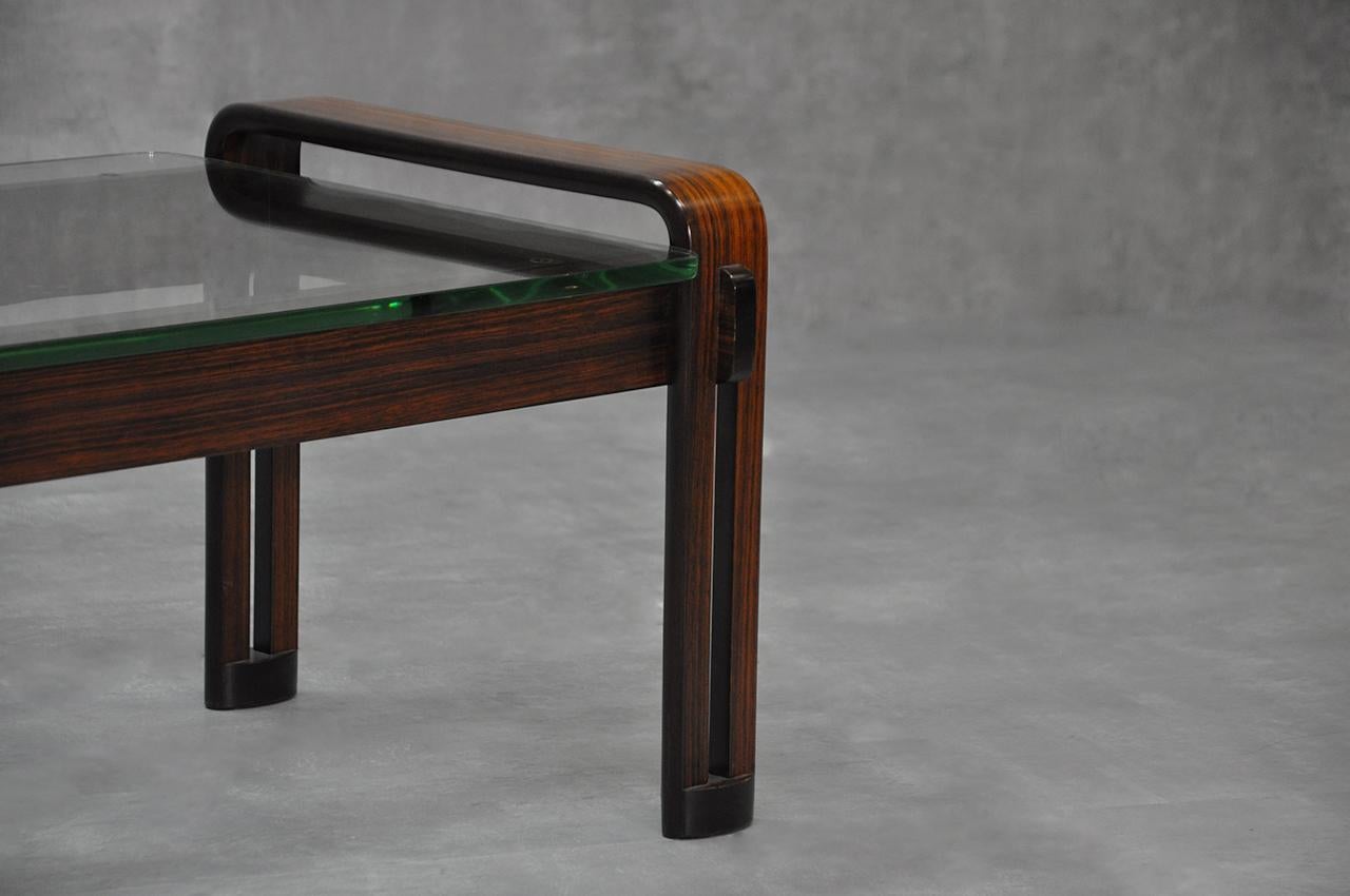 1960s coffee table. This table has a wooden structure and a glass top.