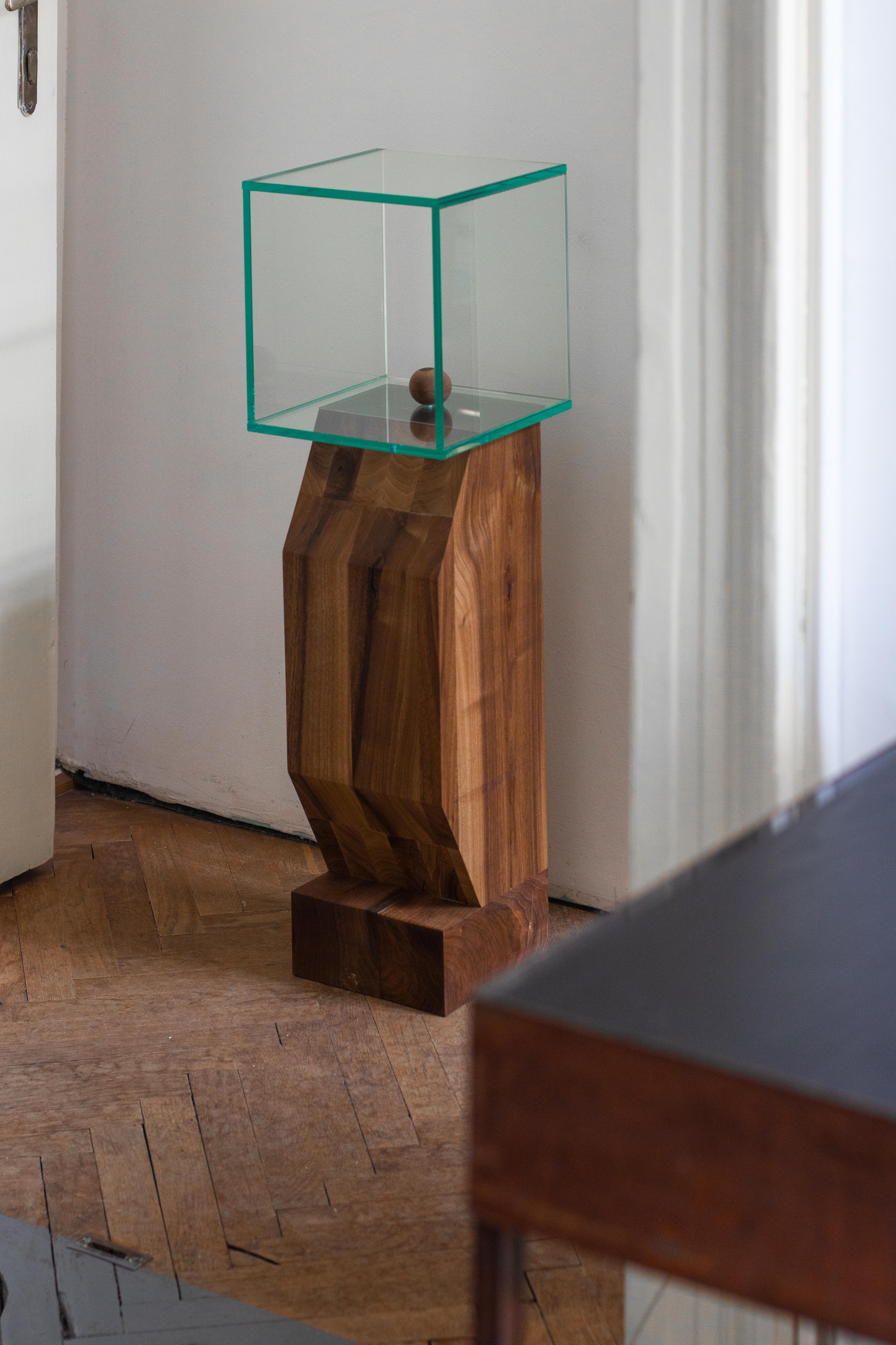 Wood and glass figure is an object part of a short family of two, that has a masive volume of walnut wood, finished with a glass cube on top. The wood volume was made out of raw planks of wood that were glued together and cut into the final shape.