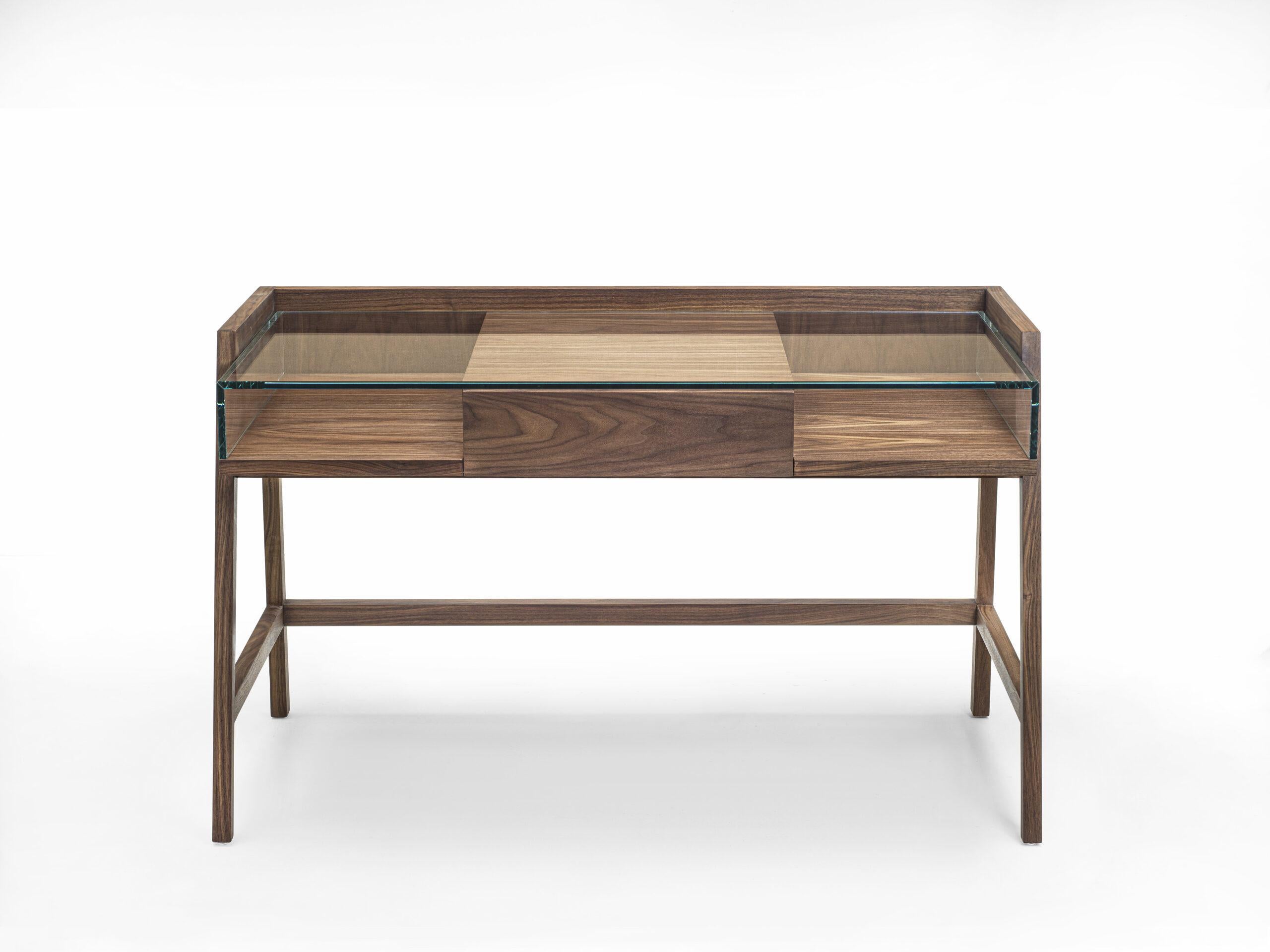Writing desk with squared lines, with structure made of blockboard and solid wood and glass top. Equipped with a central drawer assembled with dovetail joints.

Available Finishes:
Walnut or Oak (with or without knots)
Glass: Clear, Satin,