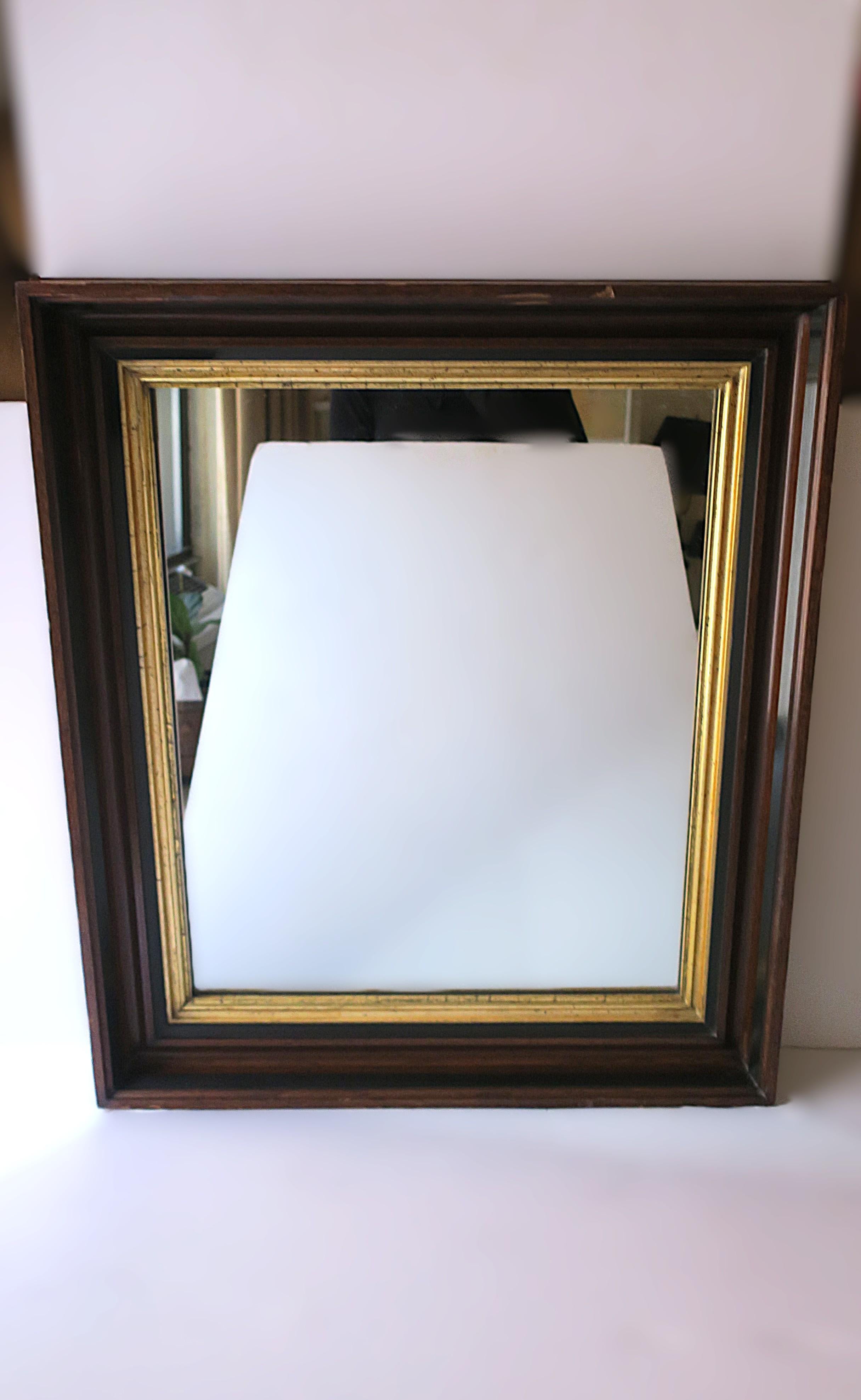 A beautiful English wall mirror with a rich brown wood and gold giltwood frame, circa early to mid-20th century, England. Handmade frame is brown, black and gold, and ready to hang as shown in last image. A great piece for a hall wall, vanity,