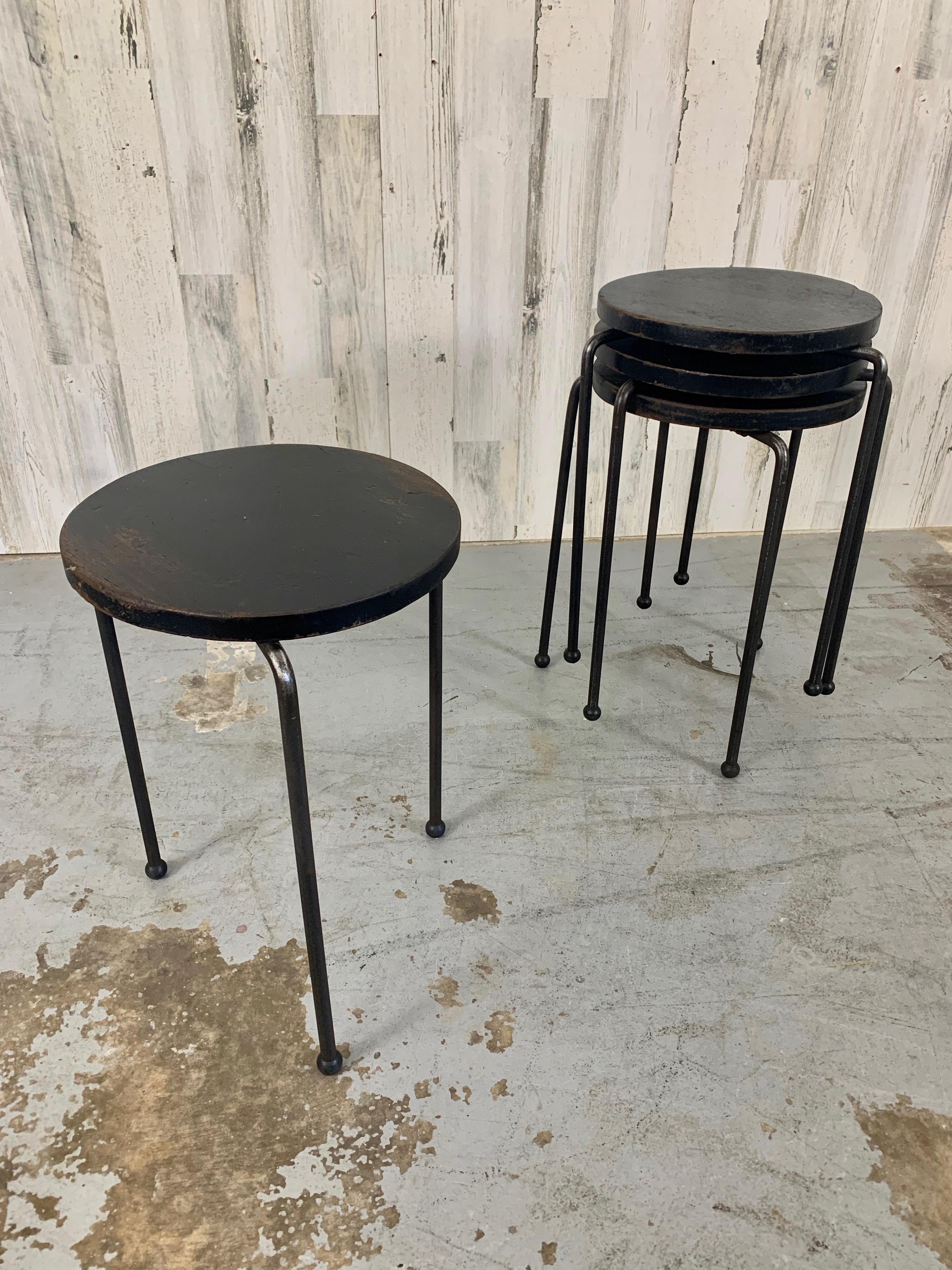 Set of four iron tripod legged stools / tables with ebonized wood tops. There is a nice patina of rust on the legs and wear on the wood tops that adds to the ambiance of age. Please see pictures.