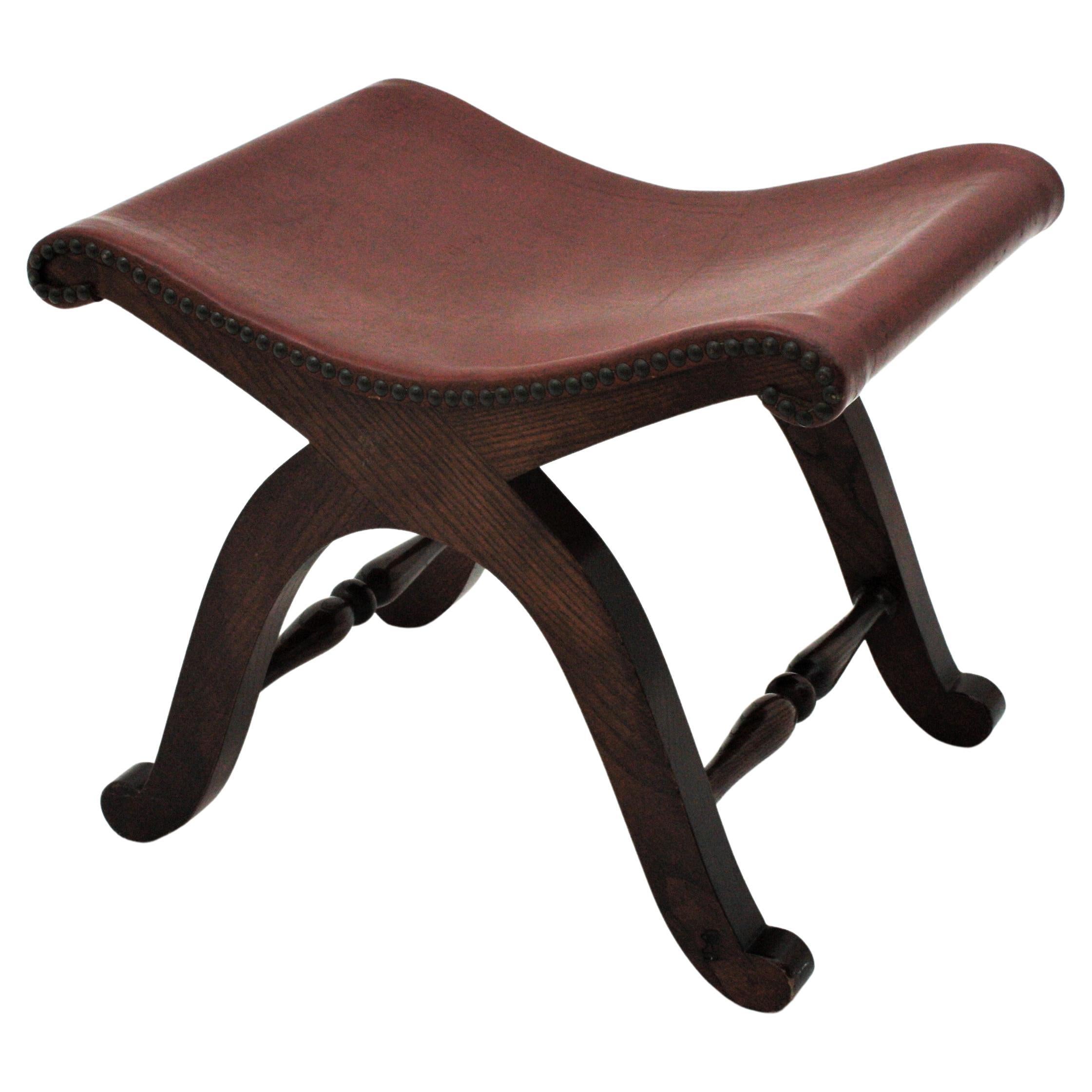 Elegant stool with wooden curule base and cognac leather seat. Designed by Pierre Lottier and manufactured by Valentí, Spain, 1940s.
This stool or ottoman is strong and sturdy and it is very good condition. The original leather seat is accented by