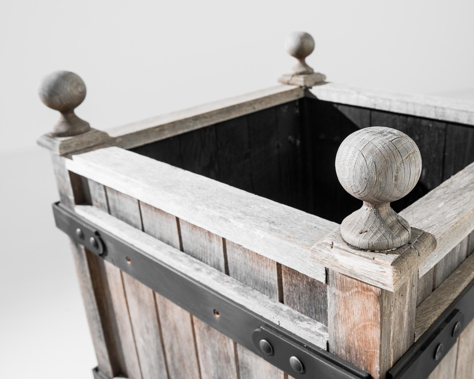 A sturdy square wooden garden planter produced in our atelier. The warm finish complements the rough adobe wood. This water resistant hardwood is a standby material in outdoor furniture and flooring. With a hint of traditional ornament, a cast iron
