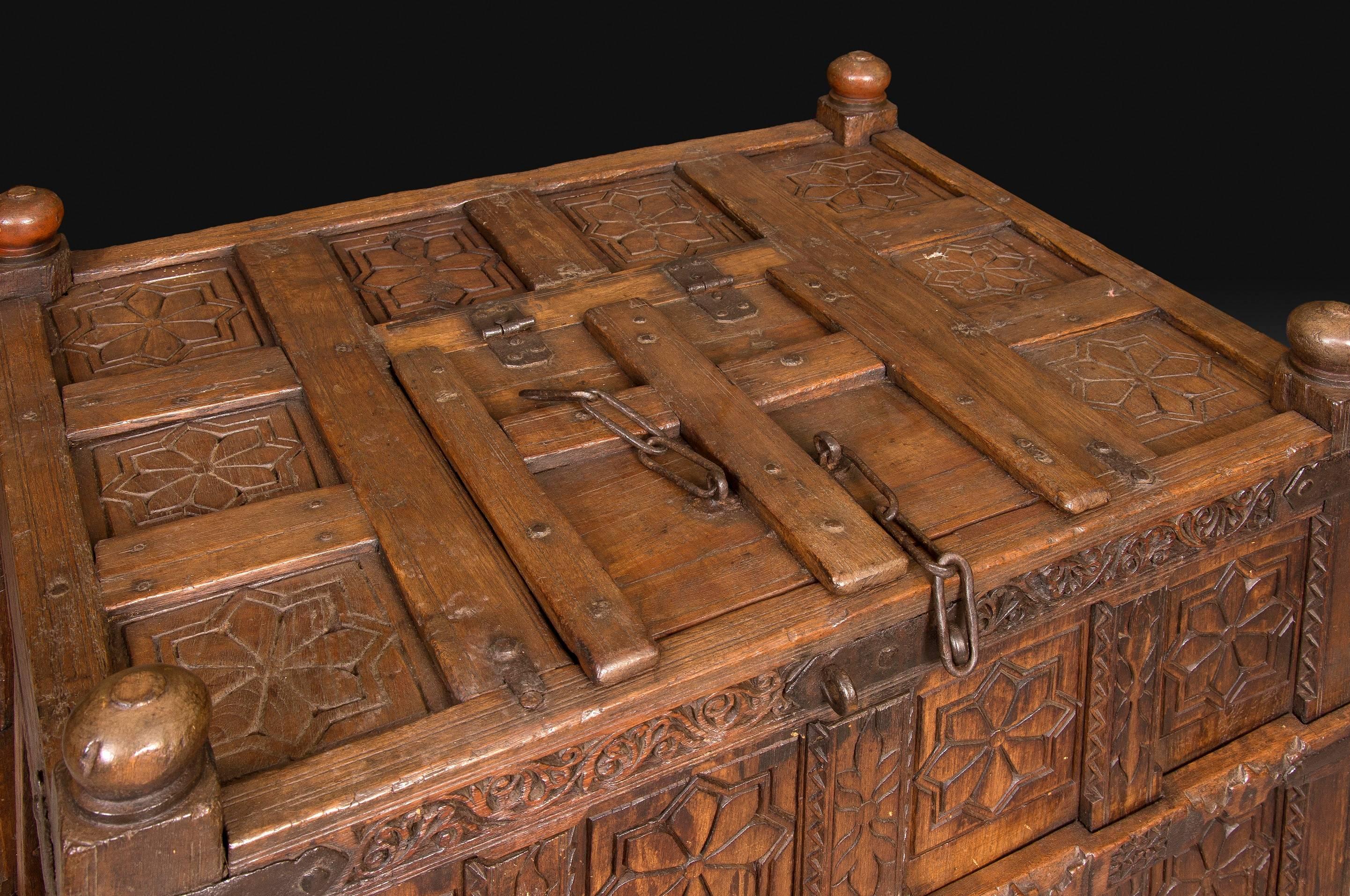 Wood and metal trunk with oriental decoration. Possibly La India, 19th-20th centuries.
Carved wooden chest raised on carved legs that presents a series of panels with simple vegetal elements carved and a division in striking cuarterones. It also
