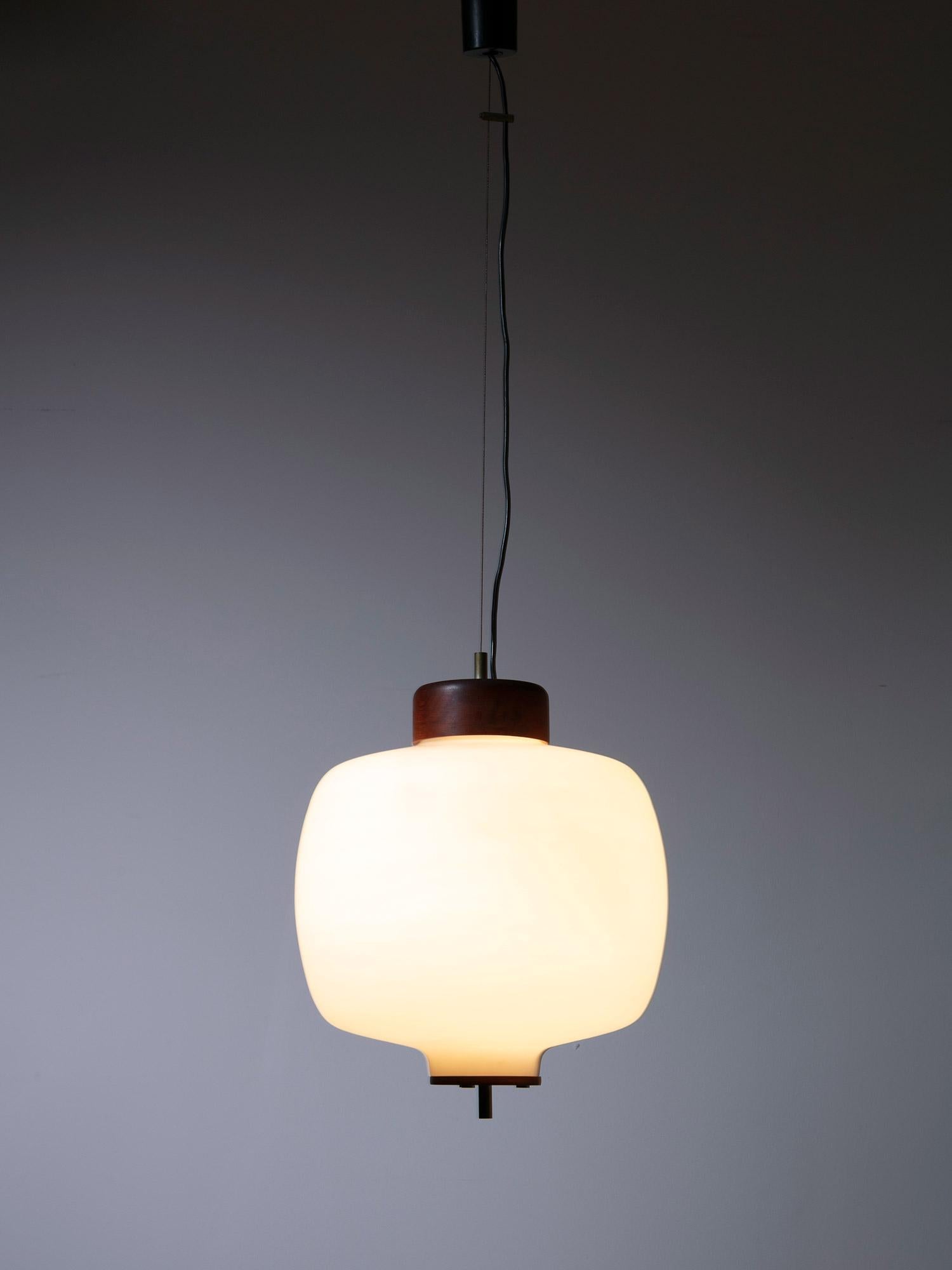 Opaline glass hanging lamp manufactured by Reggiani.
Teak and brass elements emphasizing the soft shape of the glass diffuser.