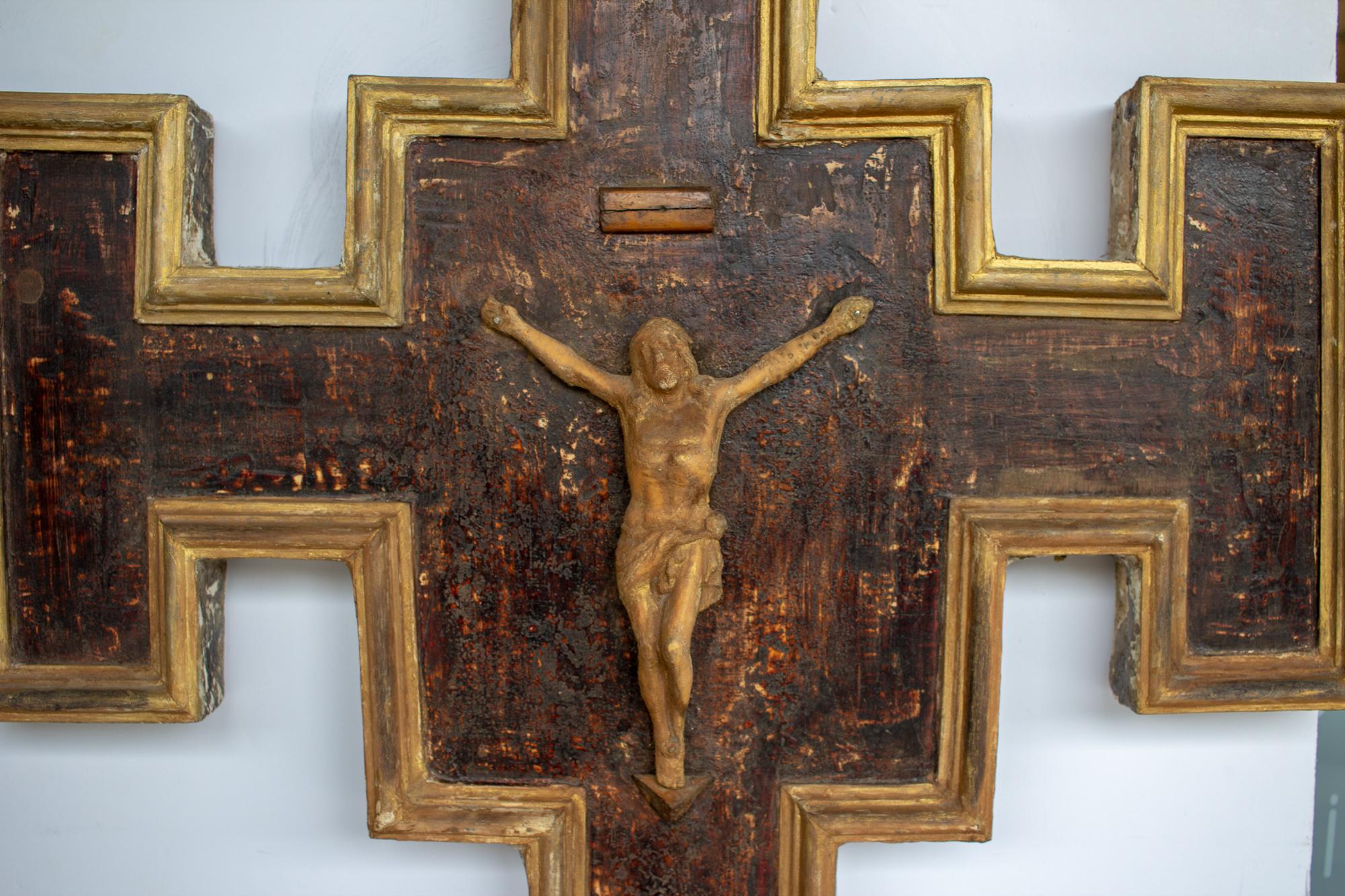 This handmade crucifix wall plaque was uncovered in Italy. The entire piece is crafted from wood and has been hand-painted with a rich mahogany brown and accented with golden gilt. The decorative edge and the hand-carved corpus of Christ are in