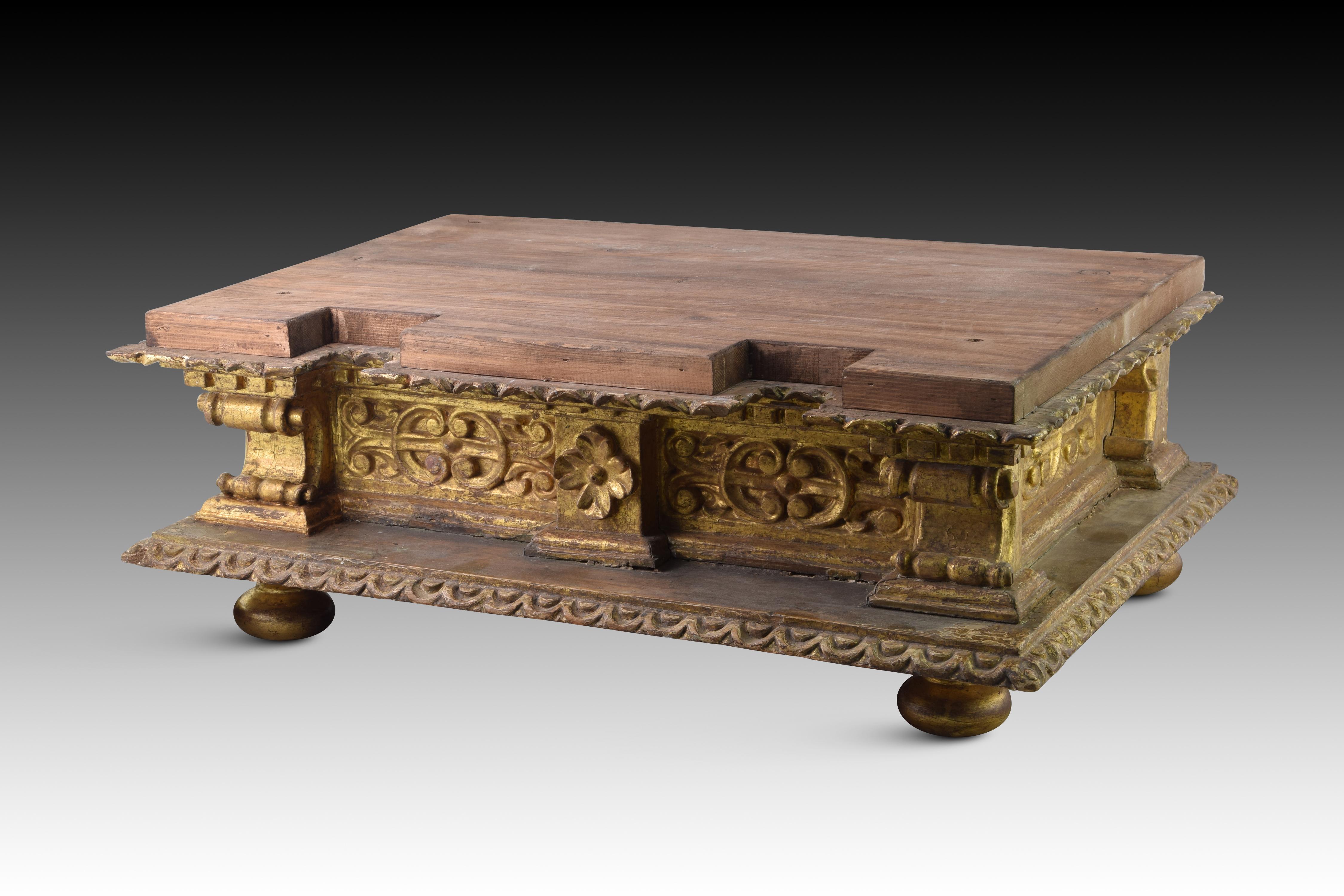 Base. Carved and gilded wood. Spanish school, 17th century. 
Base for sculpture made of carved and gilded wood with a rectangular and flat shape, slightly raised on circular legs and decorated on the front and sides with carved plant and
