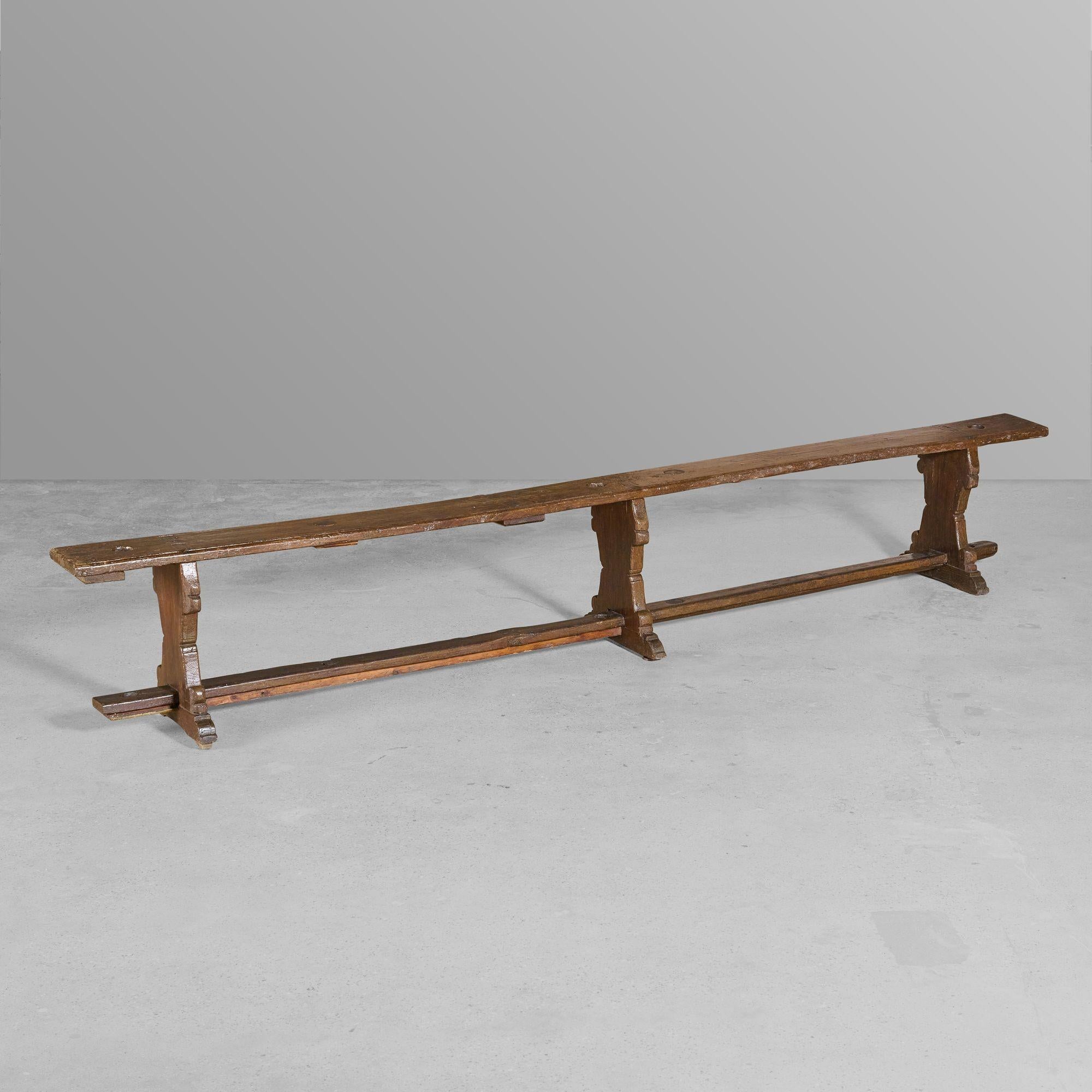 Pair of three legged wooden benches with holes for banners.
