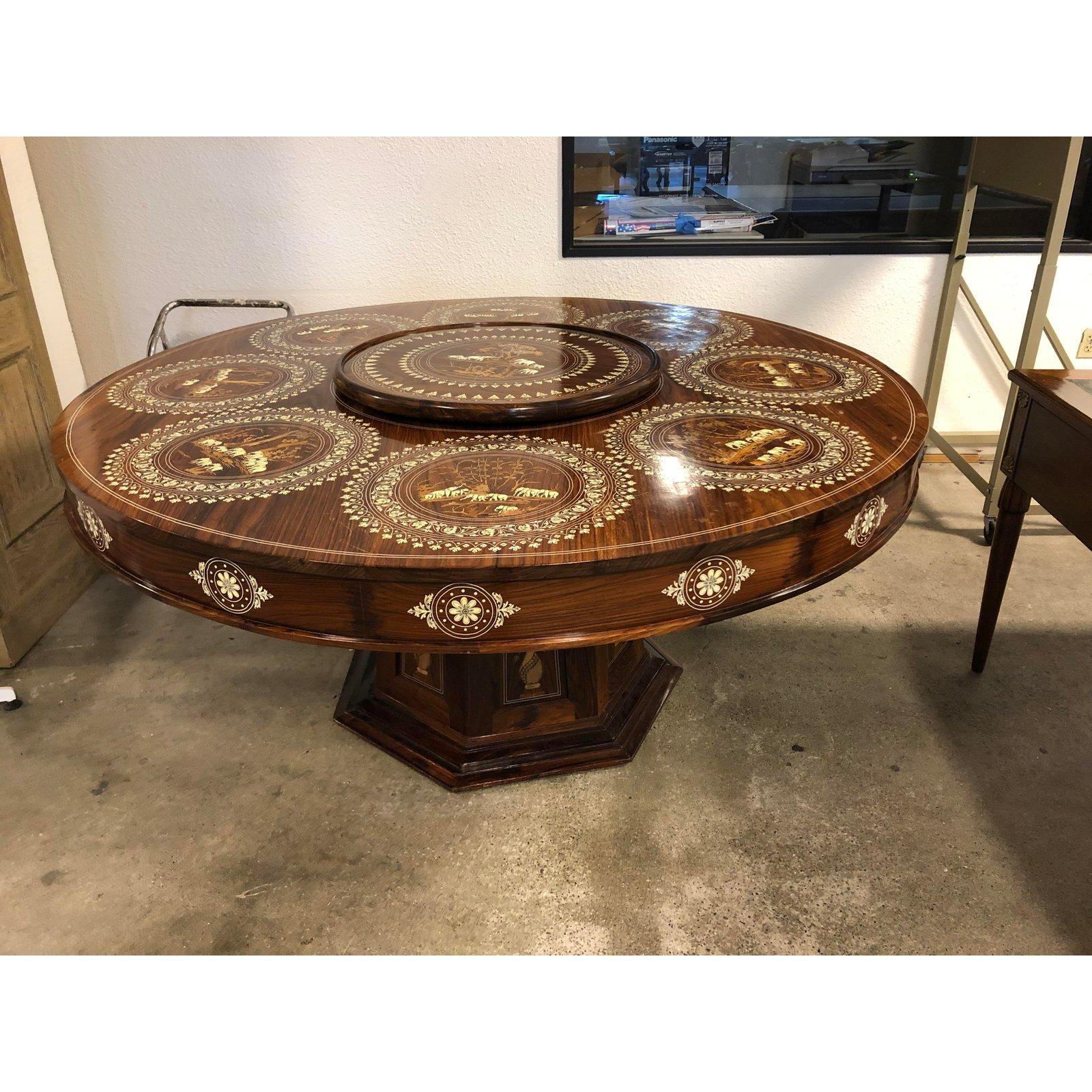 An Anglo-India dining set. This stunning pedestal dining set, table with (removable) Lazy Susan center and eight Jacquard upholstered chairs, has been inlaid bone with delicate elephant patterns and nature scenes. The designs at each place match the