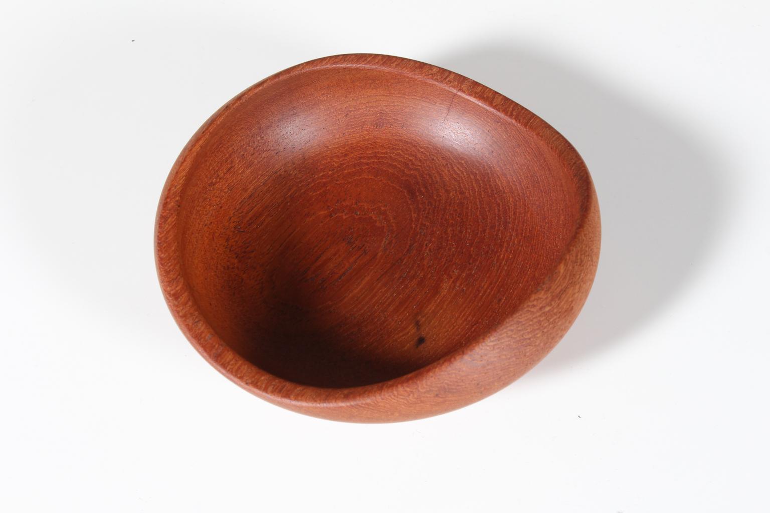 A small, turned teak bowl with organic shapes.
 
 