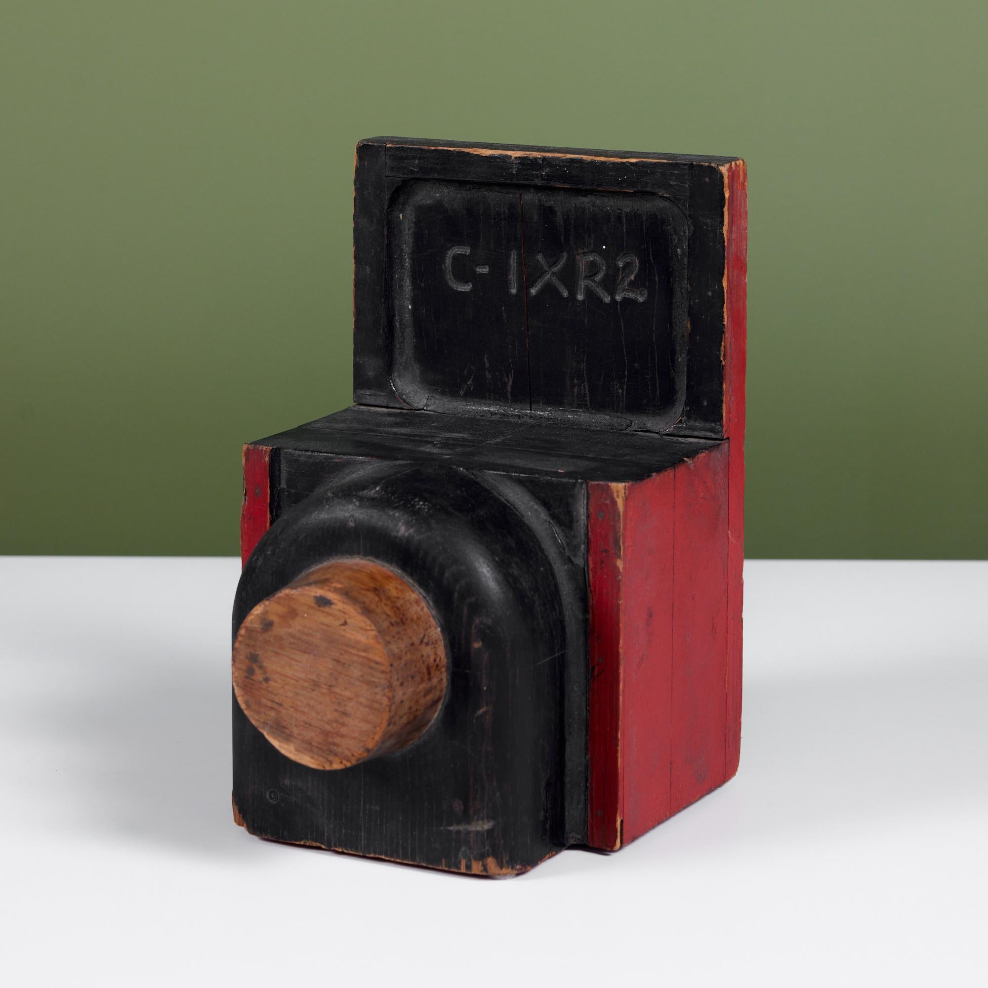 Hand carved wood camera. This playful sculpture features a painted body in black and red with the carving 