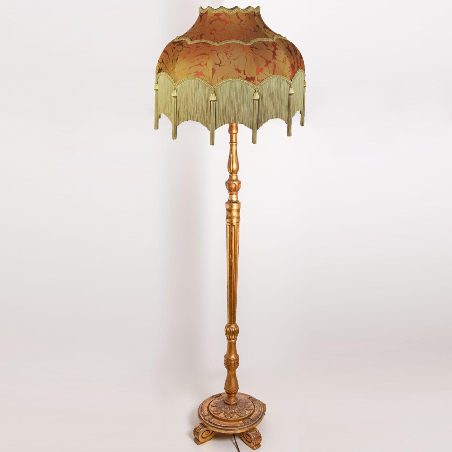 Beautiful hand carved italian wooden floor lamp with wonderful handmade fringed lampshade. The wooden base is hand carved and made in Italy around 1970.
The lamp features a striking scalloped lampshade in terracotta damask with gold fringe and