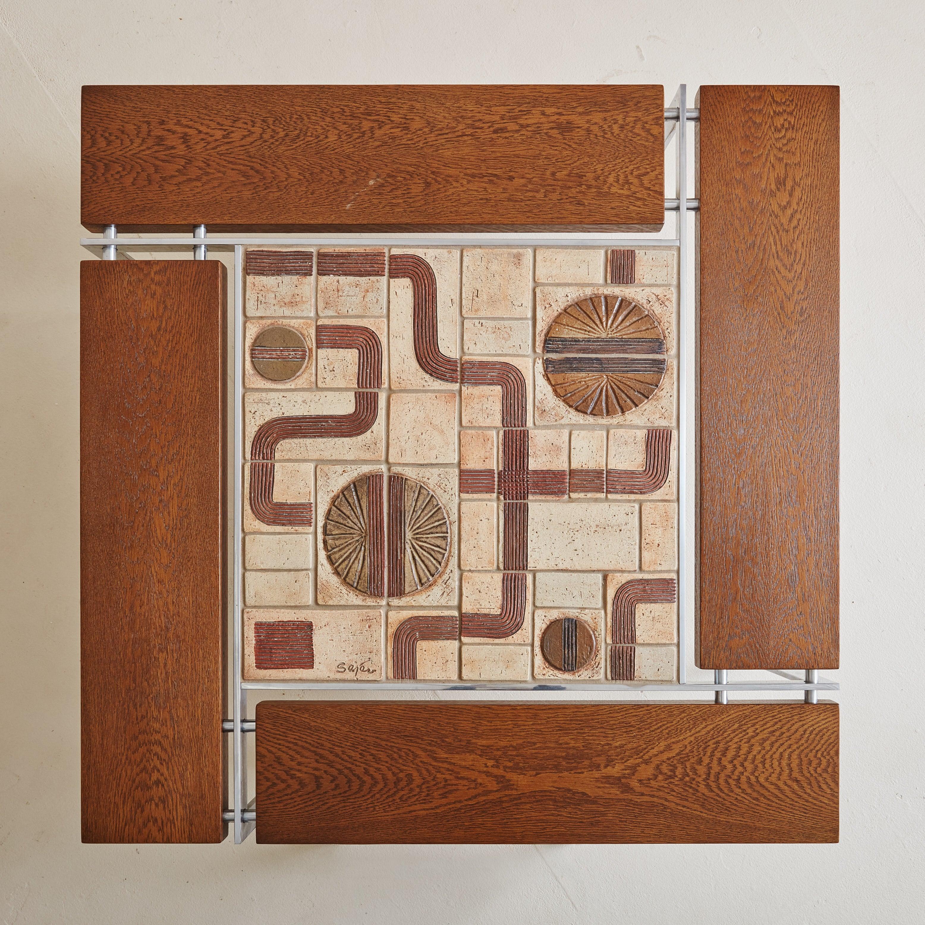 A striking Danish Modern square coffee table designed by Svend Aage Jessen & Sejer Pottery for Ryesberg in the 1960s. This table features a wood paneled top with fascinating ceramic inlay — textured tiles in varying sizes and abstract patterns flow
