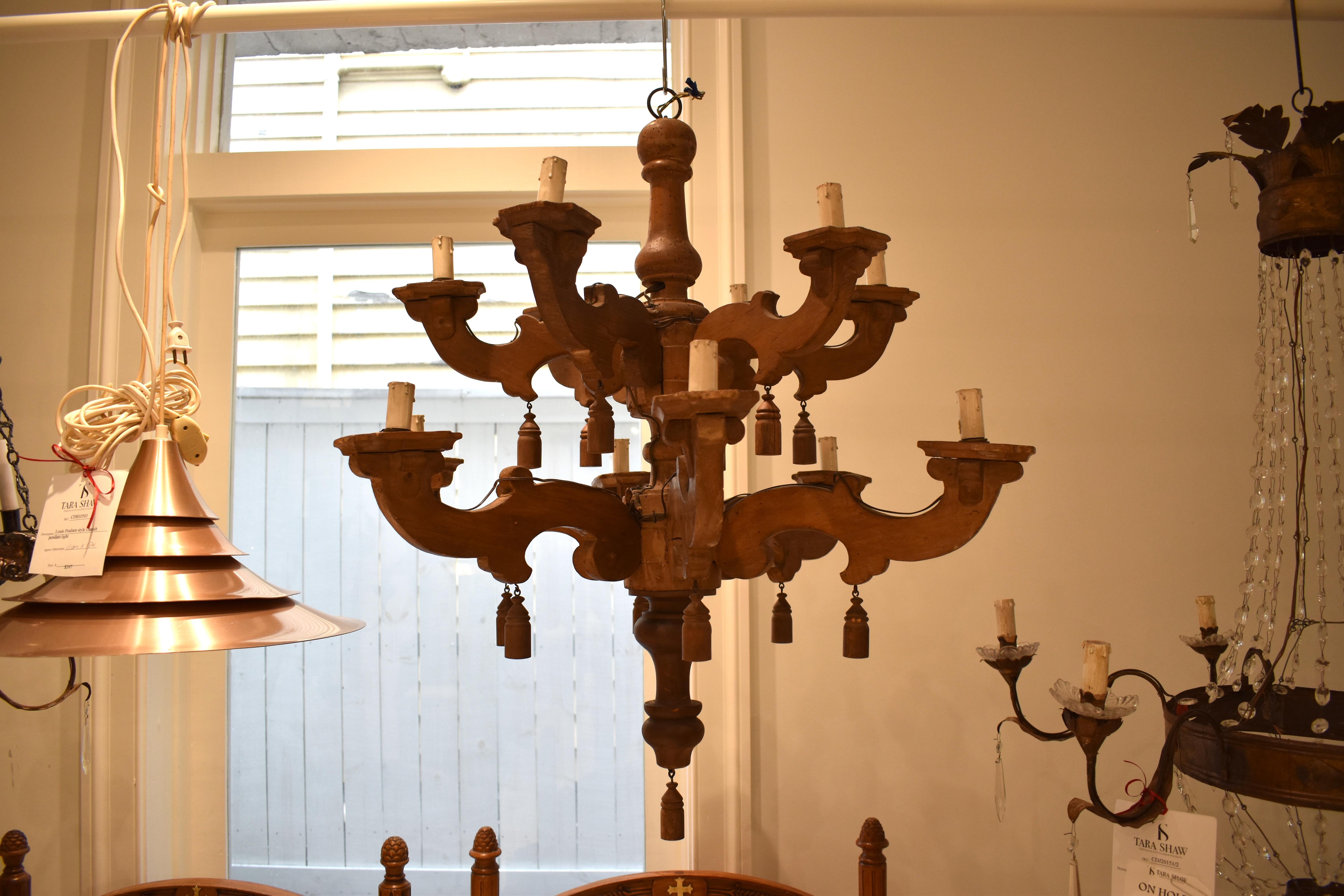 This is a most unusual all wood chandelier with 12 arms. Wooden tassels add to the whimsey. The arms are in a two tiered arrangement and carefully trimmed with small corbels around each candle. Needs to be rewired for US use. 