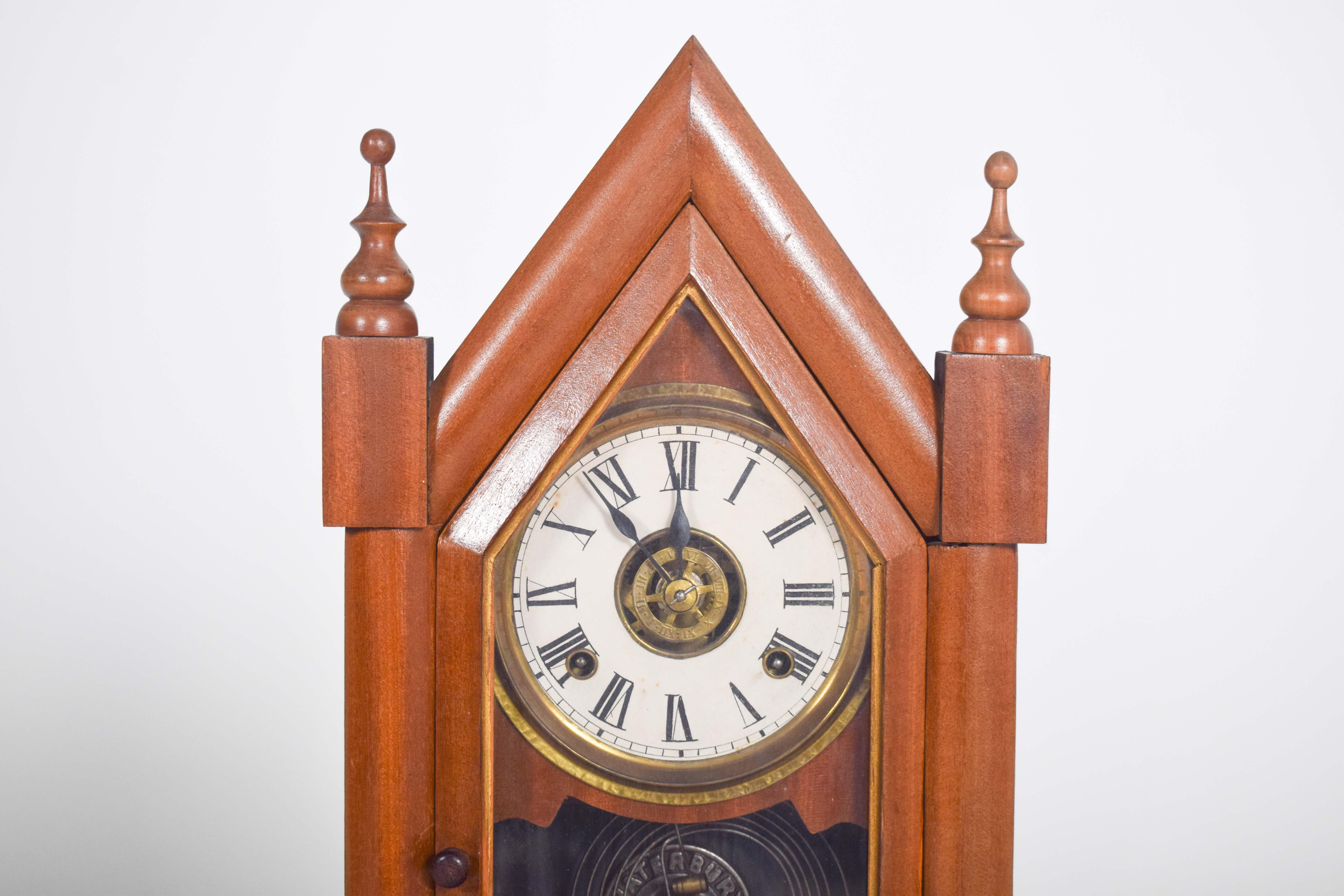 This elegant mahogany chapel clock, crafted by the renowned Waterbury Clock Co. in the USA, embodies the refined aesthetics and skilled craftsmanship of 19th-century American clockmaking. The case is designed in the shape of a Gothic-style chapel,