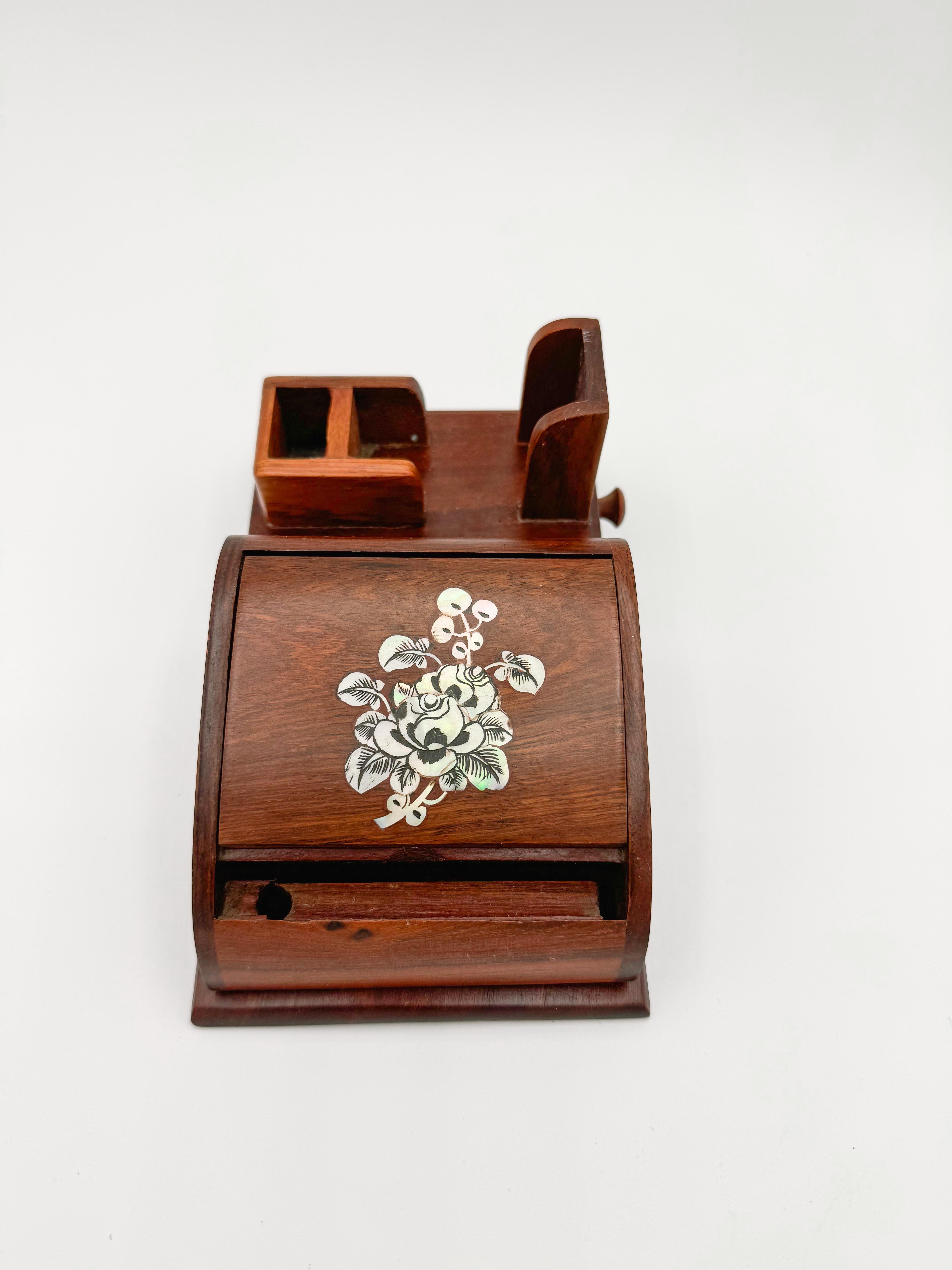 Add a touch of vintage elegance to your collection with this Wood Cigarette Dispenser Ashtray. Hand-carved with intricate details and adorned with mother of pearl inlay, this piece is a true testament to the craftsmanship.

Features:

Hand Carved