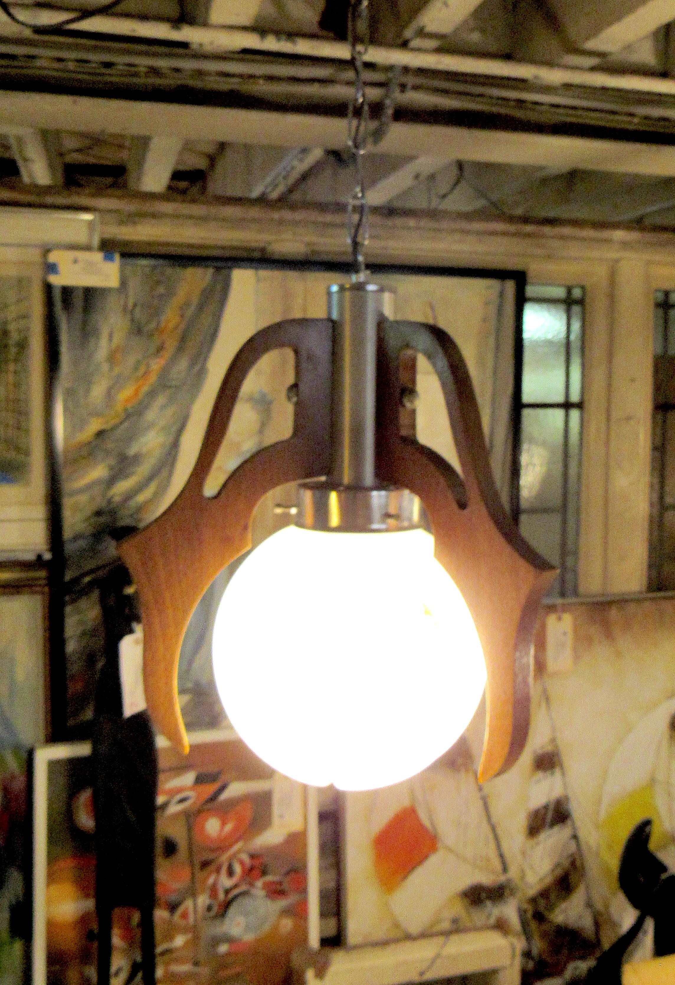 Mid-Century Modern hanging pendant lamp. 3 panels of wood forming a claw shape enclosing a spherical bulb. An undeniably unique look. Would look great in a room accompanied by other wood furniture. 

Please confirm location NY or NJ.