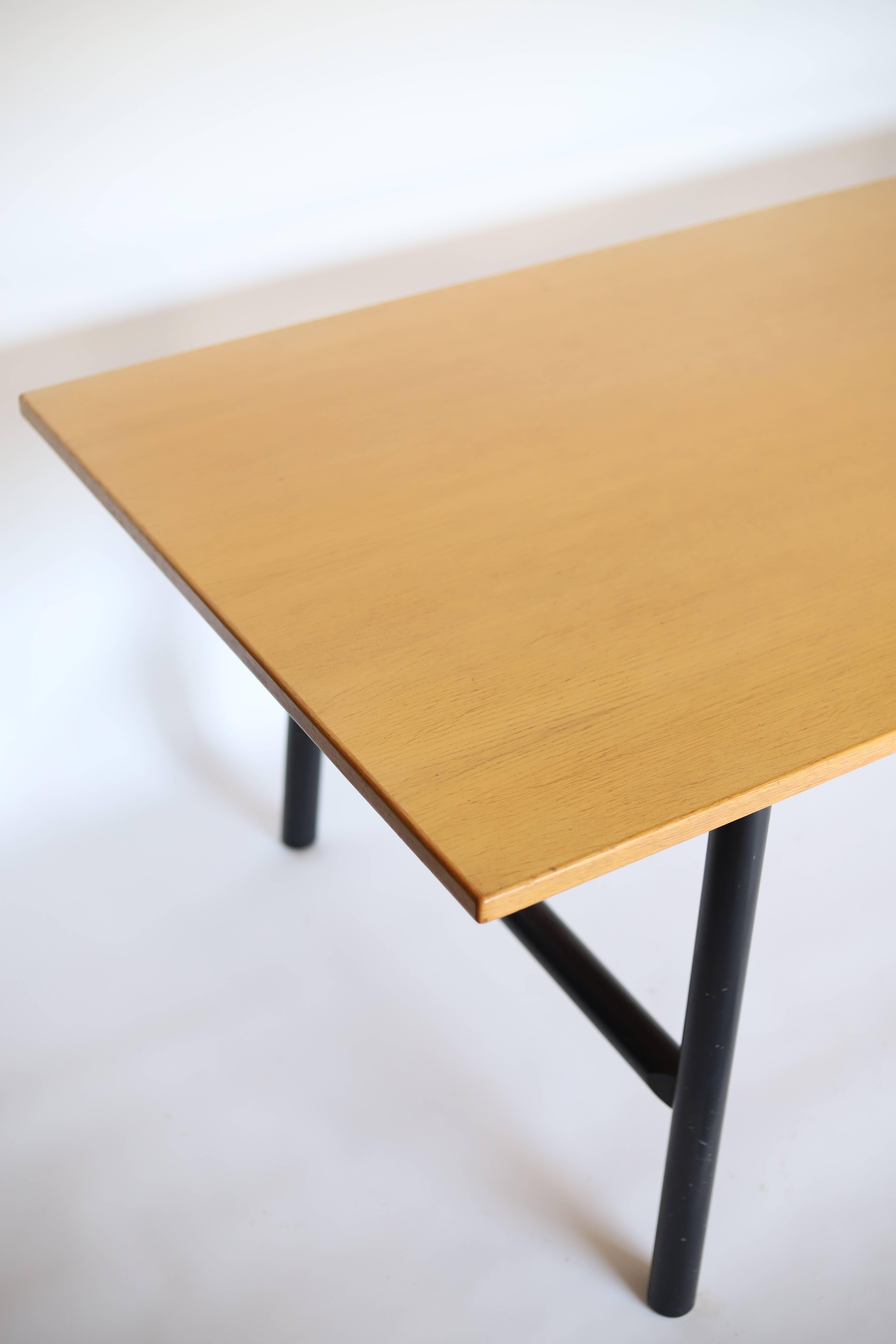 La table de salle à manger ou le bureau de l'ébéniste danois présente un plateau en bois clair et des pieds ronds noirs. Le plateau de la table est fabriqué à partir d'un bois clair de haute qualité, qui présente un aspect naturel et chaleureux. Sa