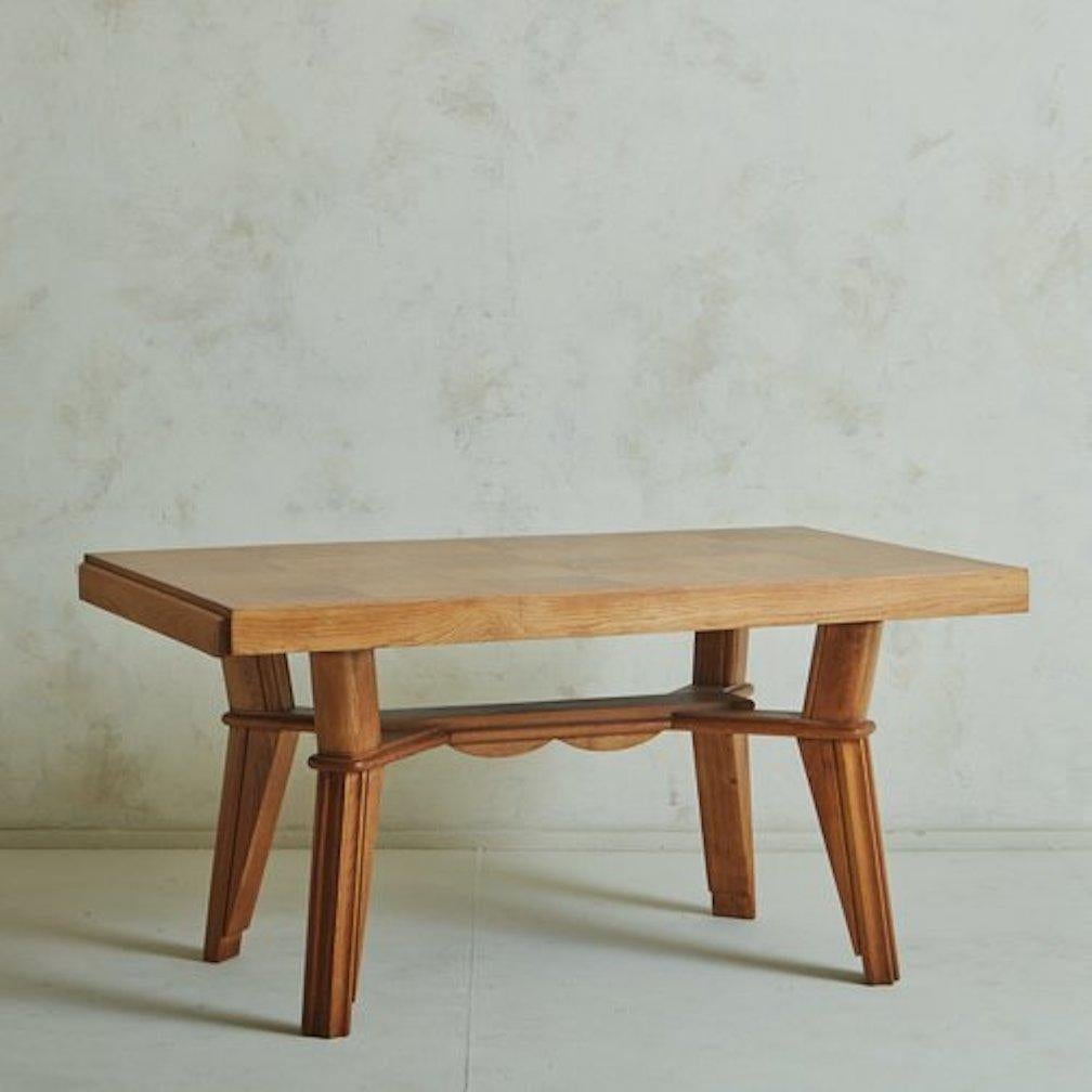 Ein französischer Holztisch aus den 1940er Jahren mit einem skulpturalen Gestell mit kantigen Beinen und geschwungenen Läufern als Details. Dieses Stück hat eine wunderschöne Parkettplatte mit einer malerischen natürlichen Holzmaserung. Eine Seite