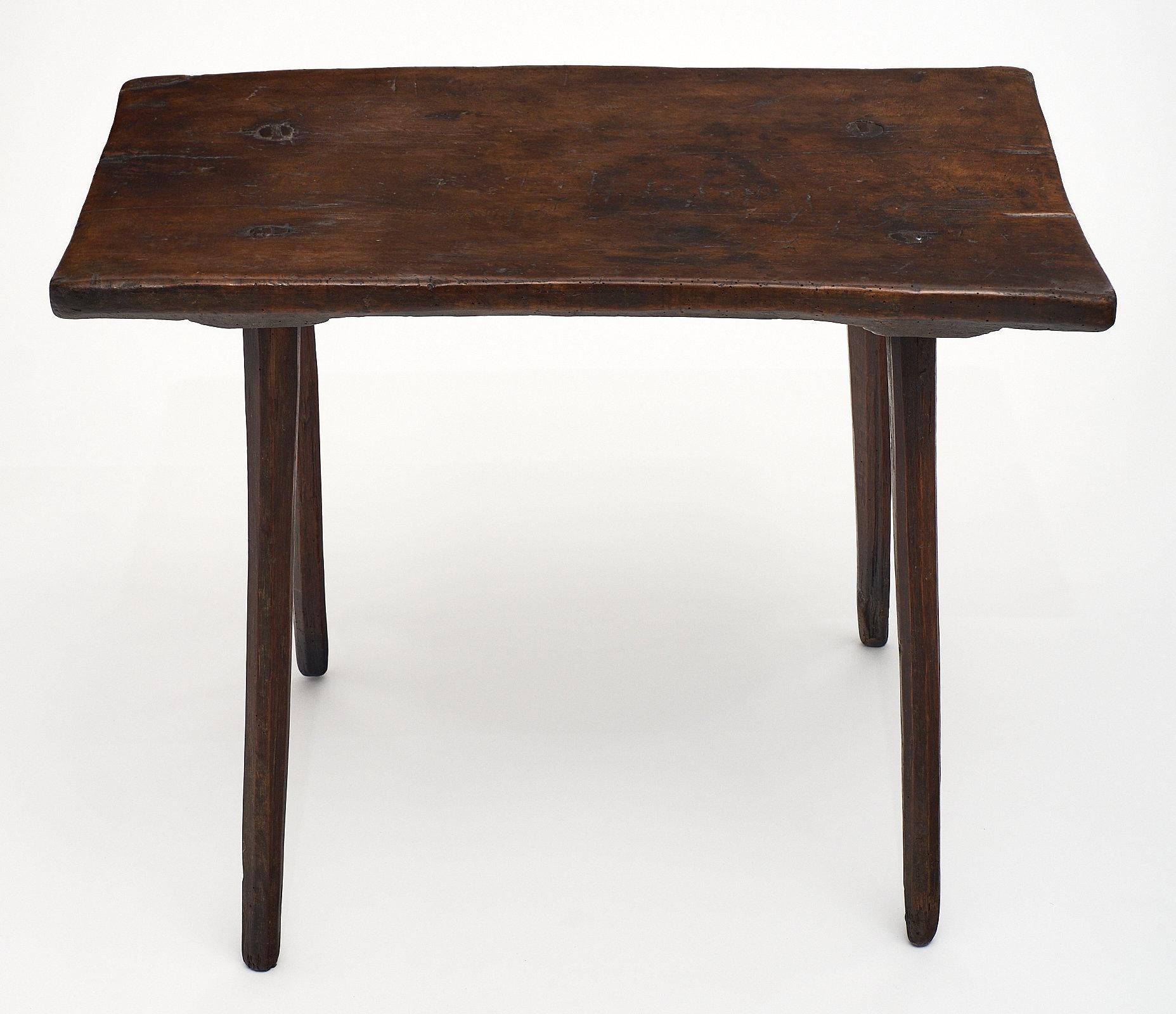 A single walnut plank Italian farm wood side table with four round, hand-carved legs pegged into the top. This primitive table has a warmth and authenticity to the form and material. We loved the feel of this Tuscan farm piece, which could be used