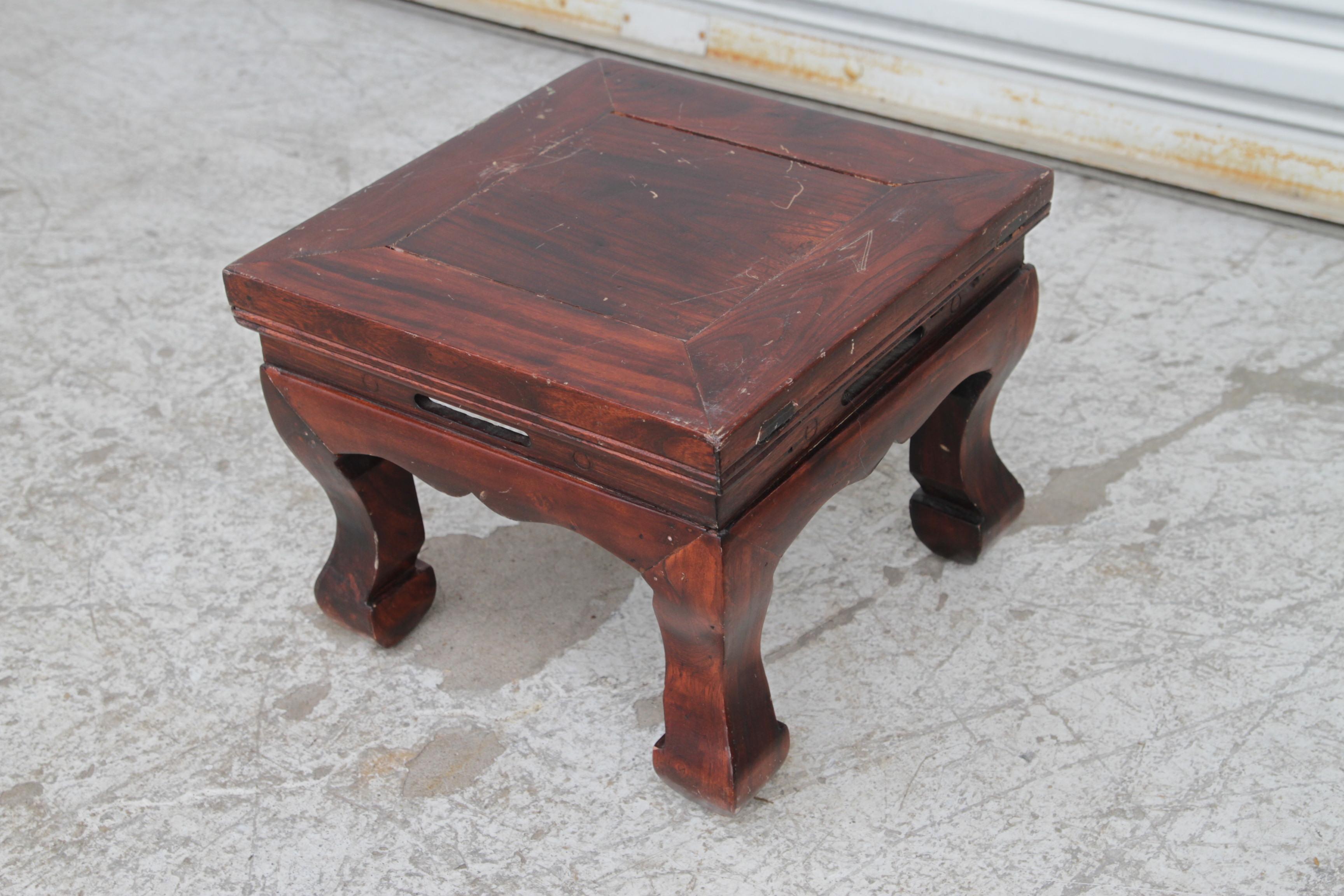 Se trata de un escabel chino de madera de Hongmu. Tiene un acabado marrón oscuro, tallas intrincadas y patas curvadas.