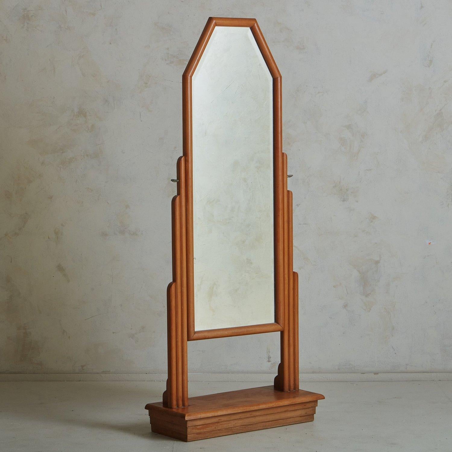 A 1930s French Art Deco style cheval mirror featuring an angular wood frame with cylindrical tiered detailing. This mirror has a rectangular undulated base and ornate metal hardware, which allows the position of the mirror to be adjusted. Unmarked.