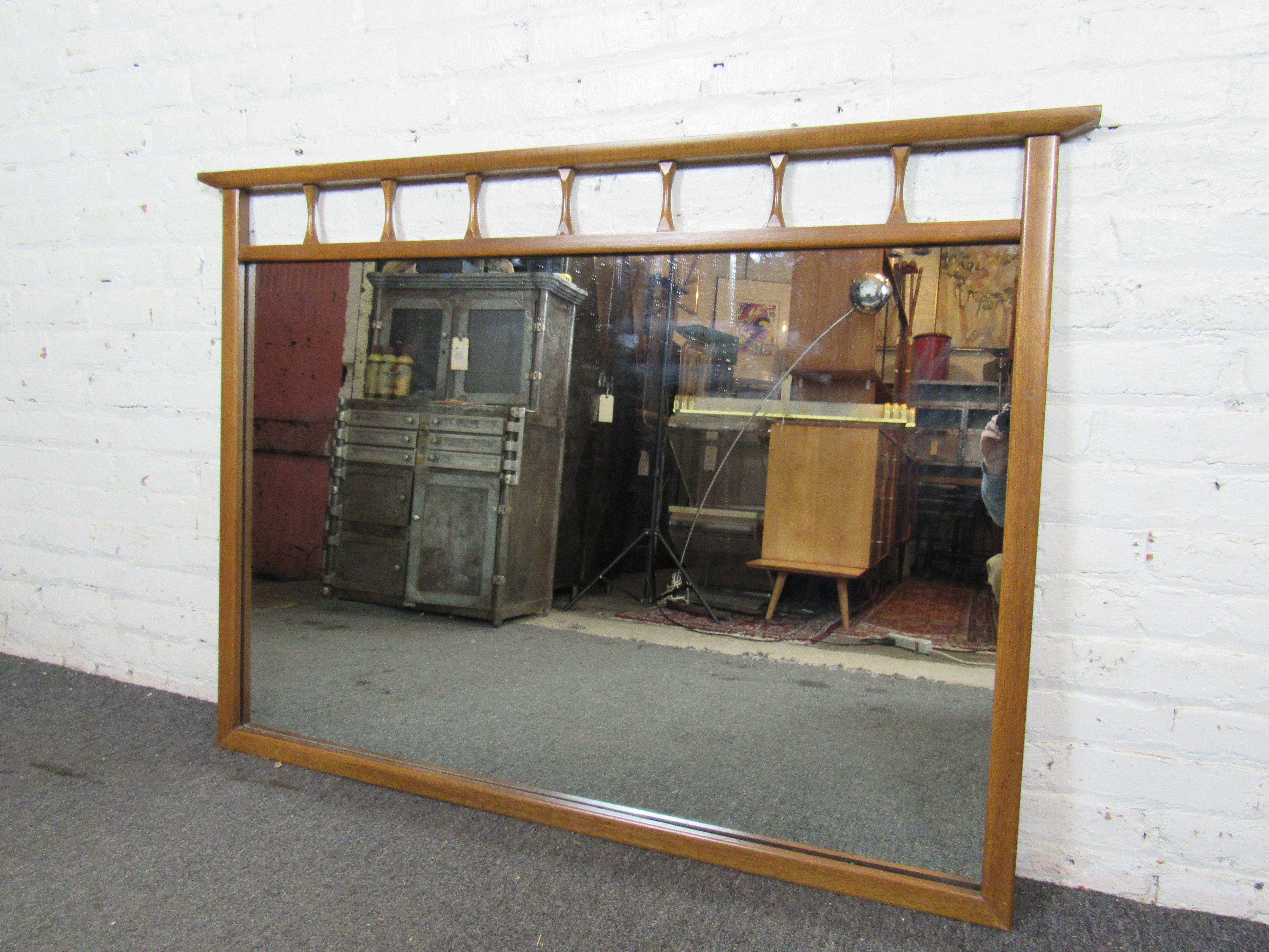 This large vintage wall mirror has a uniquely-sculpted wooden frame that can add a Mid-Century Modern touch to any space. Please confirm item location with seller (NY/NJ).