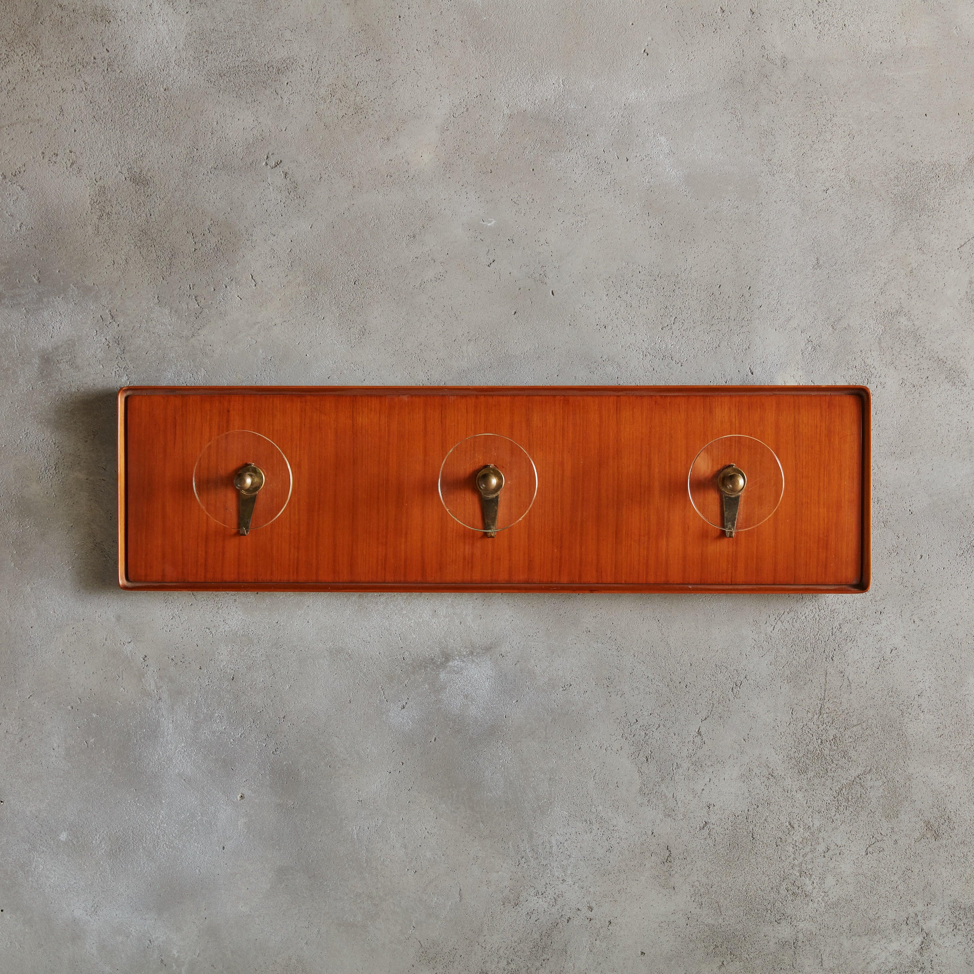 A 1960s Italian rectangular wall mounted coat rack composed of wood in a warm, cherry hue. This coat rack features three exaggerated round glass knobs and patinated brass hardware. Sourced in Italy, 1960s.

Condition: Good overall vintage condition.