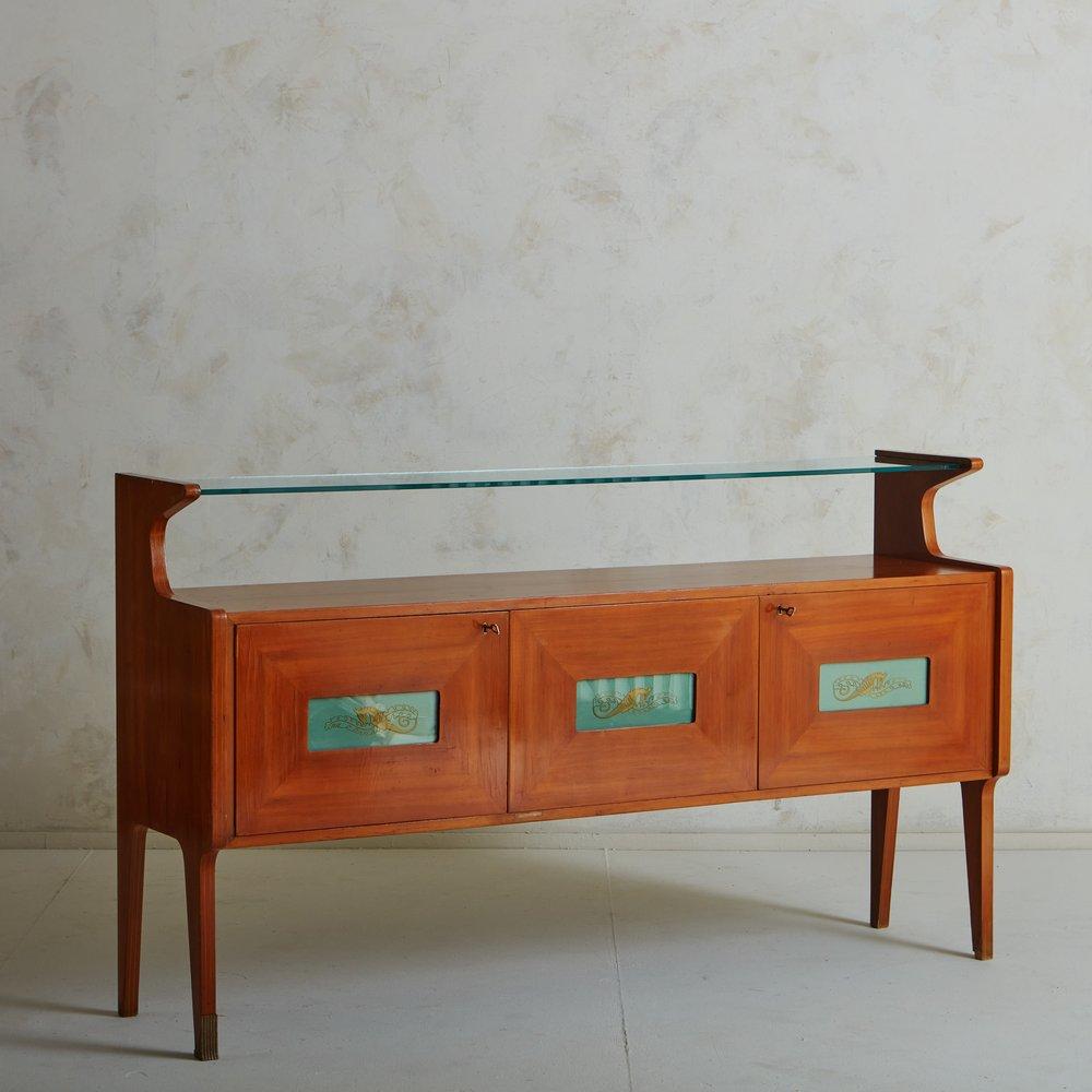 A beautiful 1950s Italian credenza in the style of Vittorio Dassi. This piece has three cabinet doors, each with an inset rectangular green glass detail featuring a gold seahorse motif. It has a wood veneer with beautiful graining and subtle inlaid
