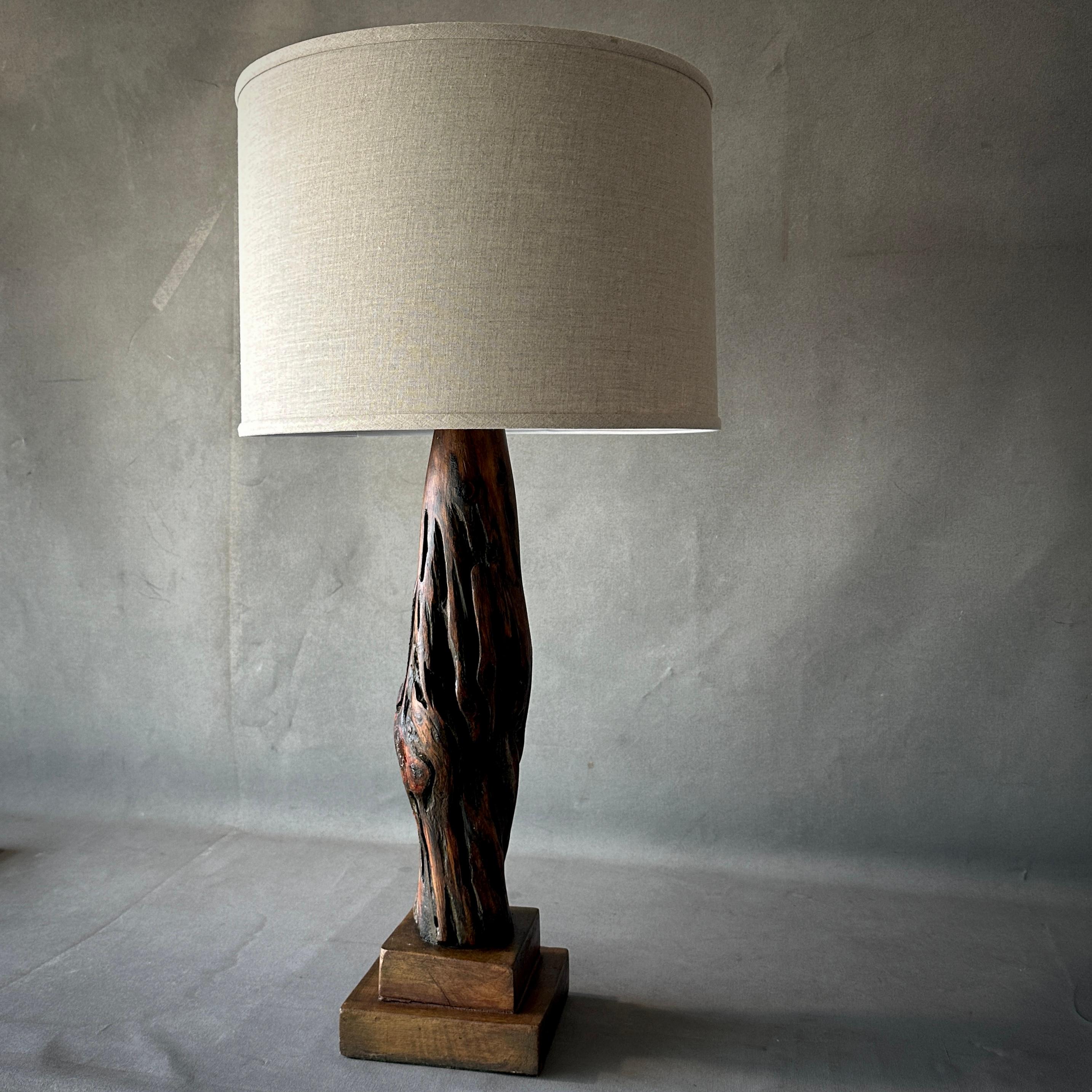 Esta lámpara belga de mediados de siglo, combina elementos de madera natural con una pantalla rectangular de lino marfil para producir una estética sensual y orgánica. La base, esculpida a partir de una sola pieza de madera, muestra la belleza bruta