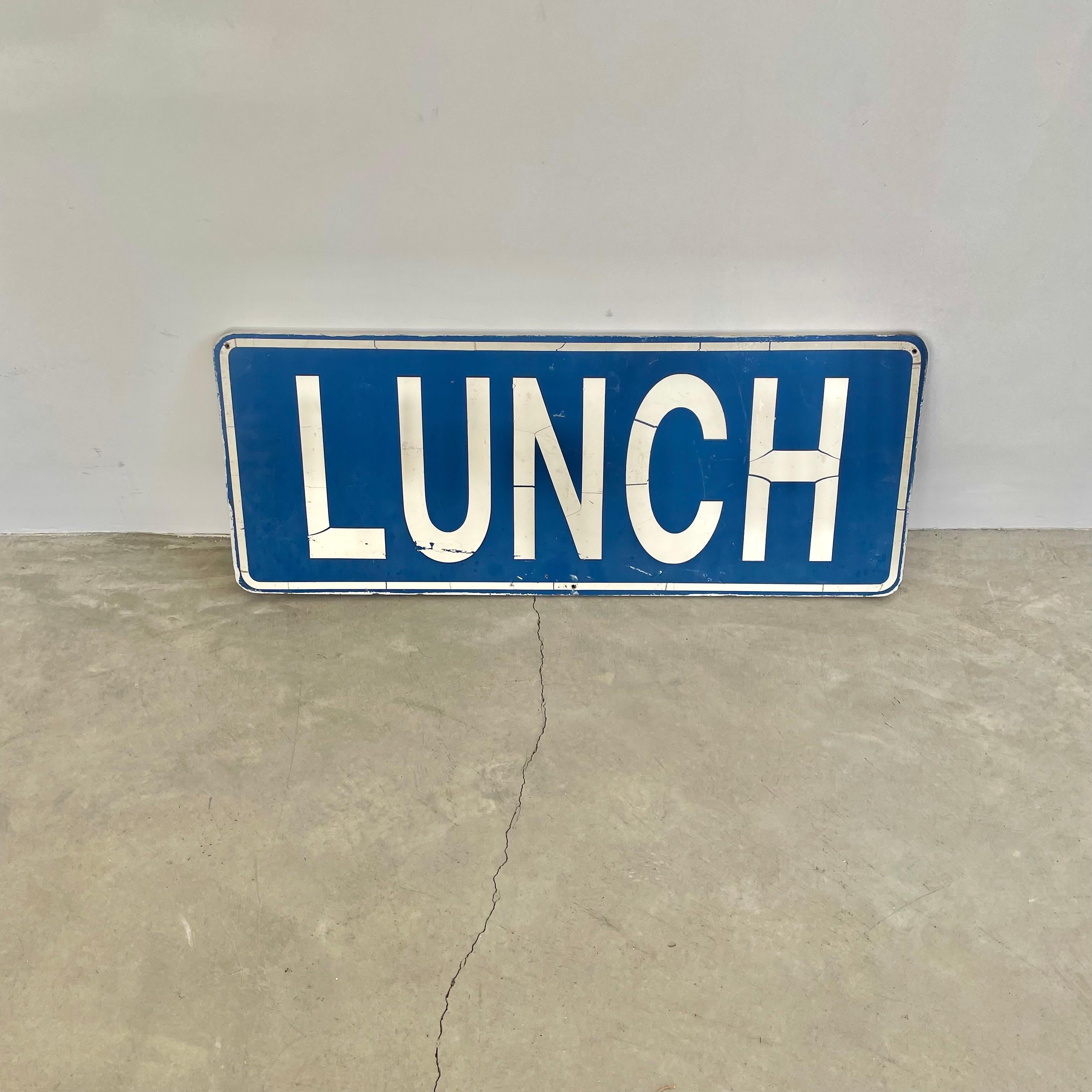 Prominent 1980s reversible LUNCH sign in a unique and bold blue base color with white font and borders. The reverse side features colorful flowers and the word 