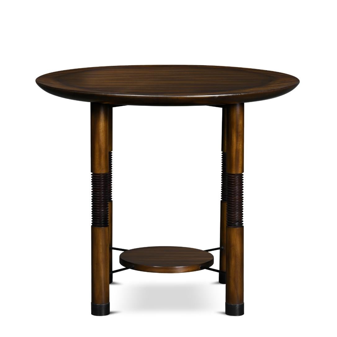 This lamp table is made of wood and has a round table top. Its turned legs have decorative cymbal details and are finished with metal tips. The pannel is connected to the legs by a crossed metal support.
 