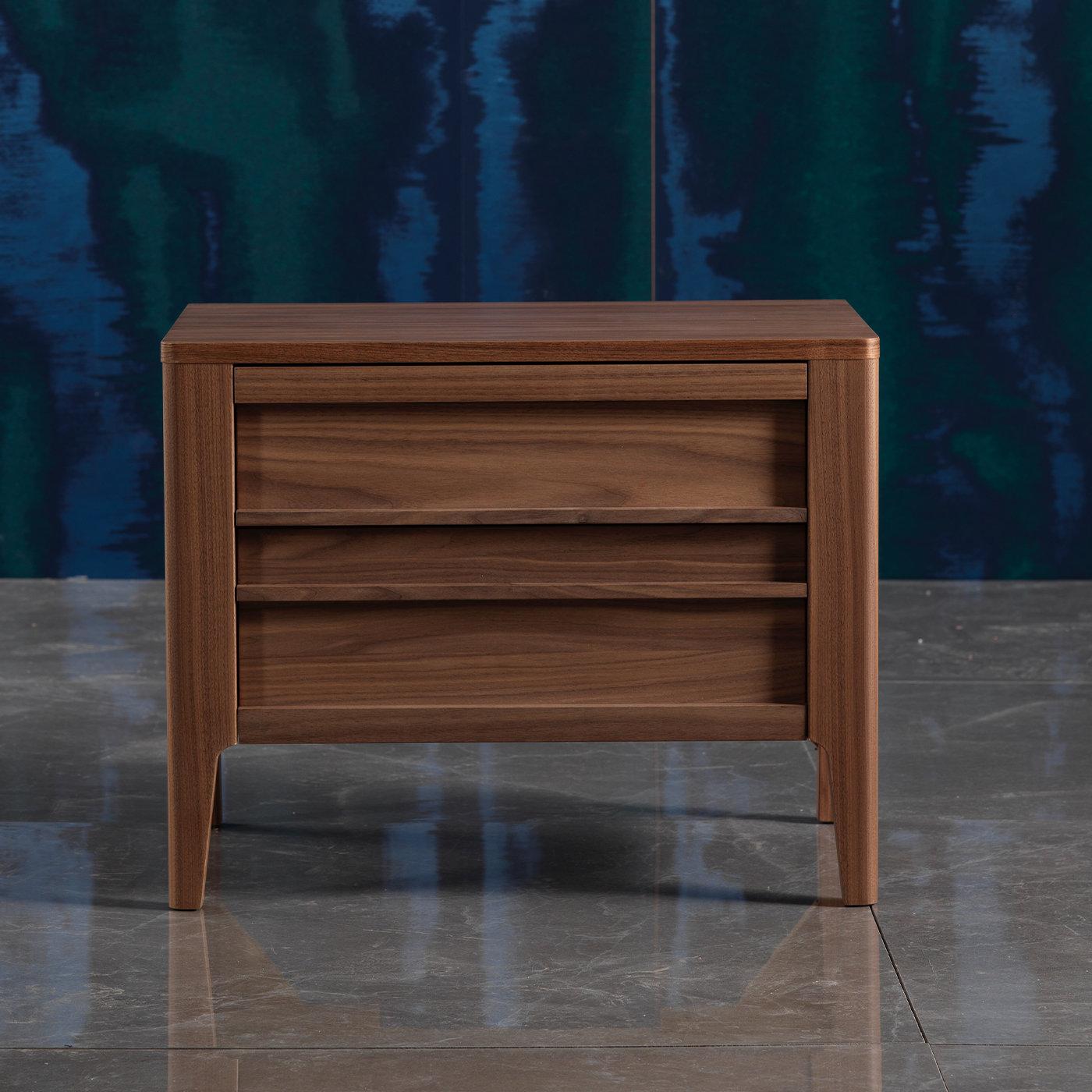 This walnut wood nightstand is sleek and elegant while practical, and is perfect to be set on either side of a bed for added elegance and practicality in any bedroom. This nightstand rests on slim wooden legs and boasts two drawers that have wooden