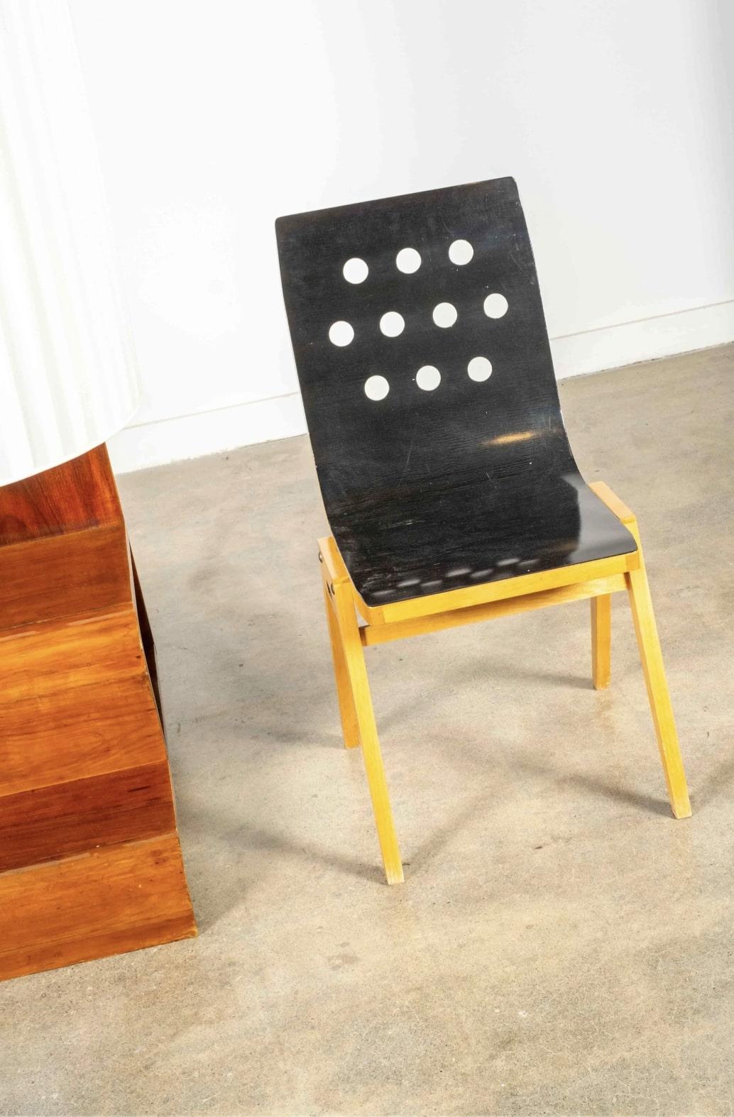 Die Perforationen dieses modernistischen Beistellstuhls sind eine verspielte Note in einem hart arbeitenden Möbelstück. Die geschwungene Sitzfläche ist nur auf einer Seite in schlichtem Schwarz gehalten, was man sieht, wenn man den Stuhl zum ersten