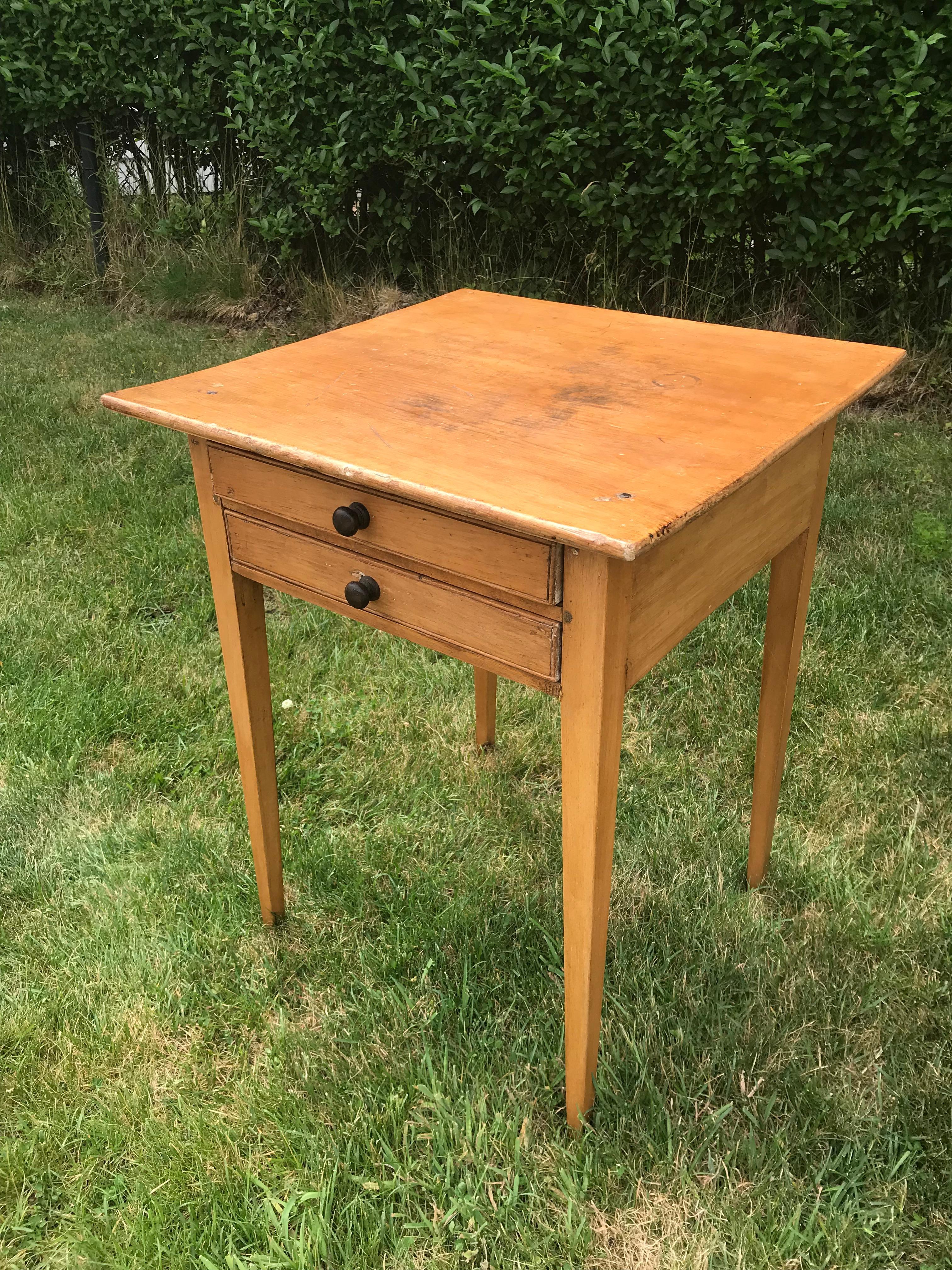 Wood side table, two drawers with dark knobs.