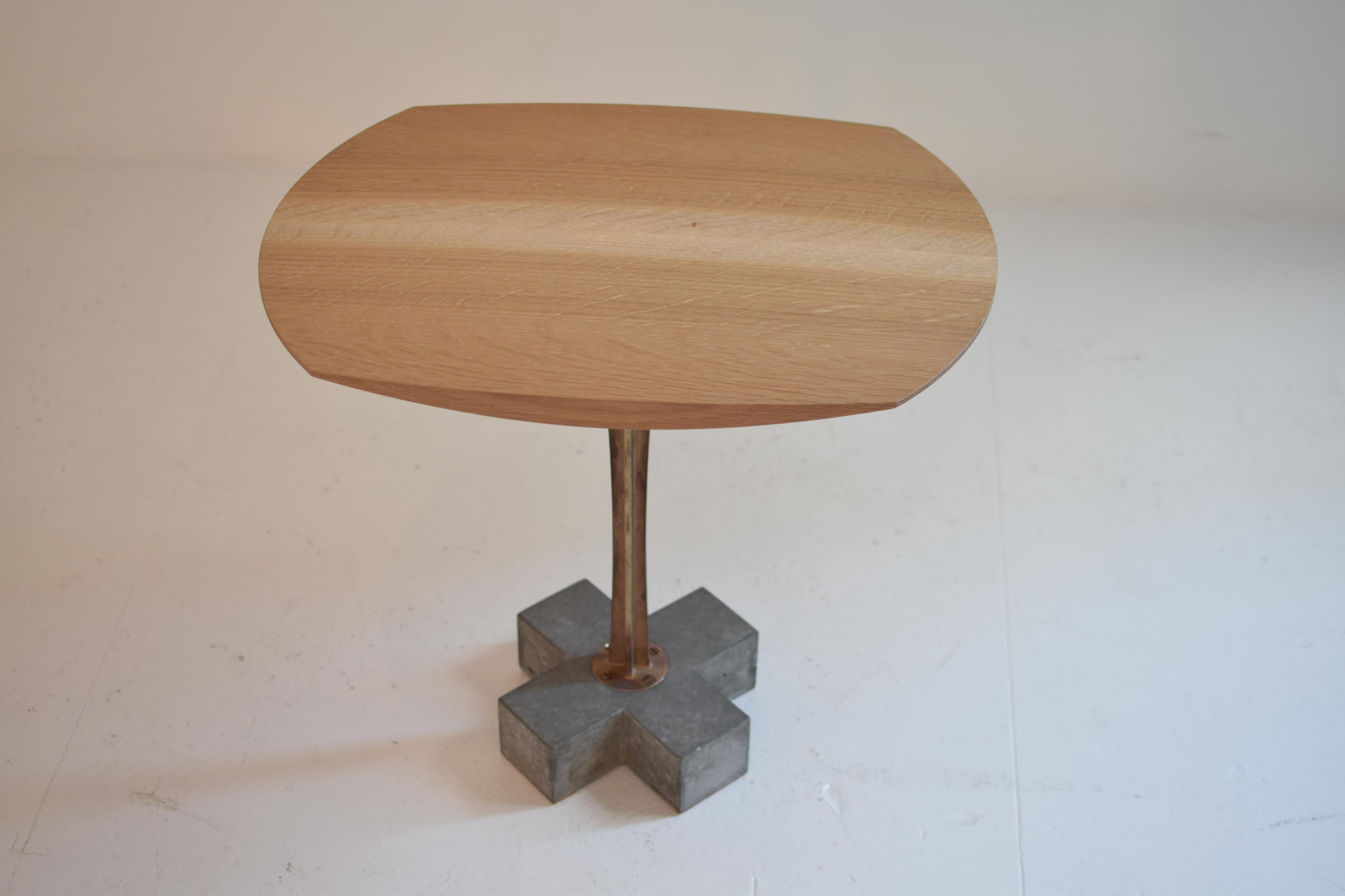 X side table

The subtle curves of this side table are an exquisite complement to the rigid geometry of the concrete cruciform base. The wooden tabletop is lathe-turned to a high polish, while the raw bronze stem curves upwards to meet