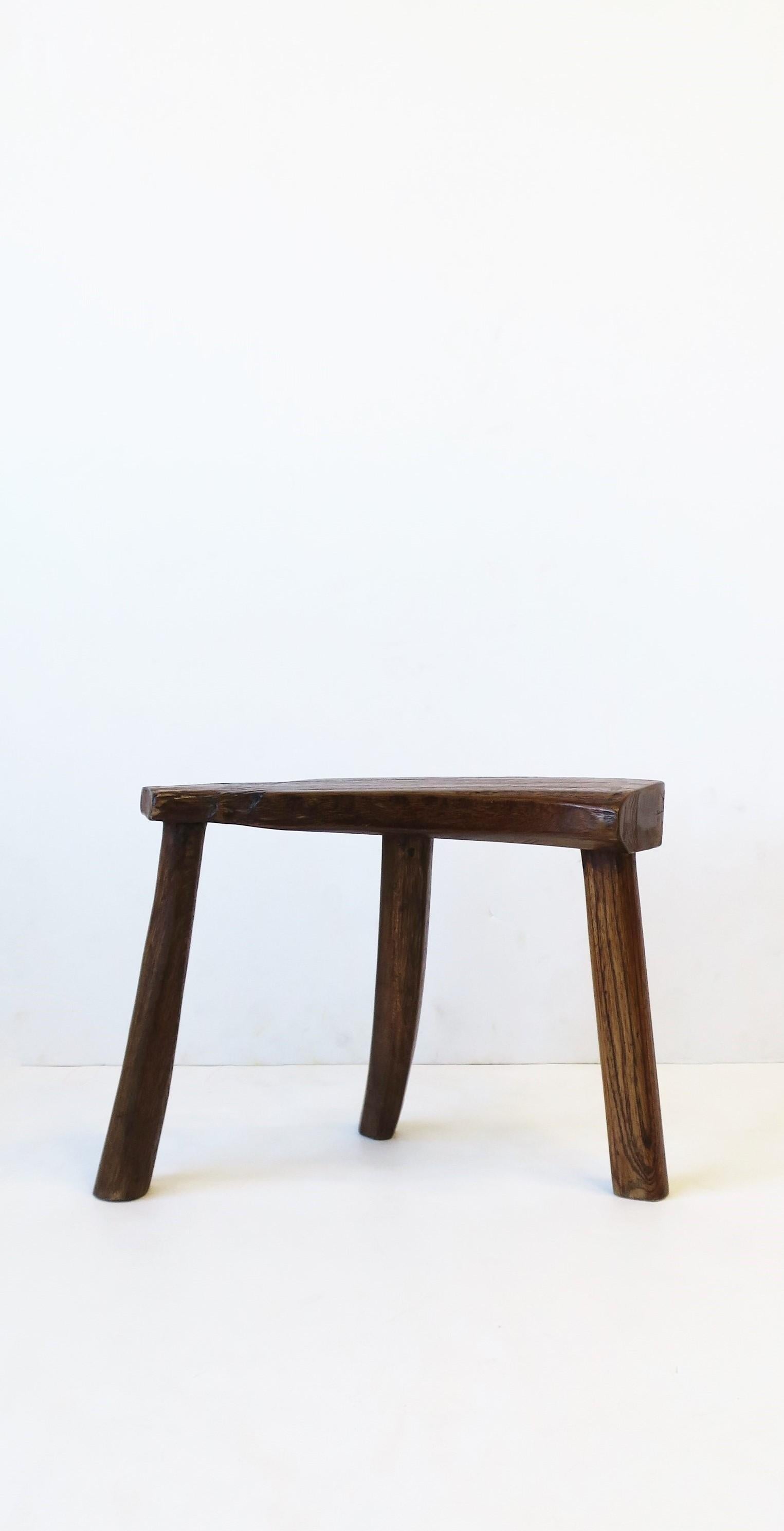 A small and low wood stool with tri-legs. Piece can serve as a seat, foot stool, and can also hold a drink, small books, etc. Convenient size, as demonstrated. Dimensions: 4.63