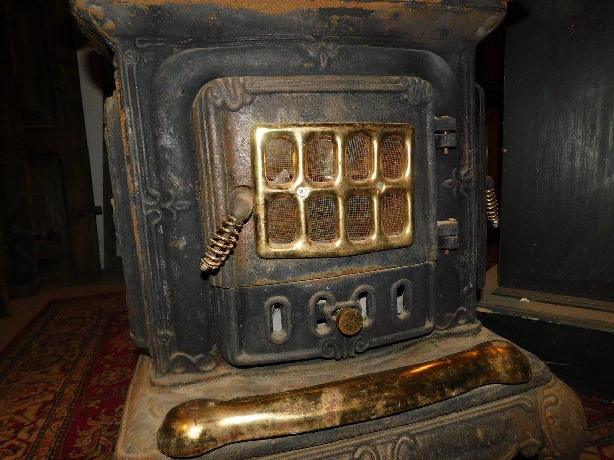 Estufa de leña, marca Parlor Stove, en hierro fundido negro, acabados en latón dorado siglo XX